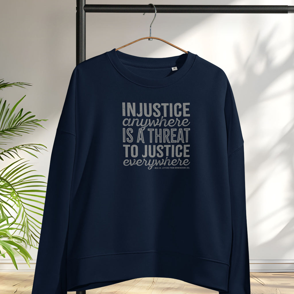 Navy sweatshirt with bold text reading “Injustice anywhere is a threat to justice everywhere” quote from Martin Luther King Jr, MLK Jr, Letters from Birmingham jail — civil rights protest apparel for activists. Hanging on a hanger.