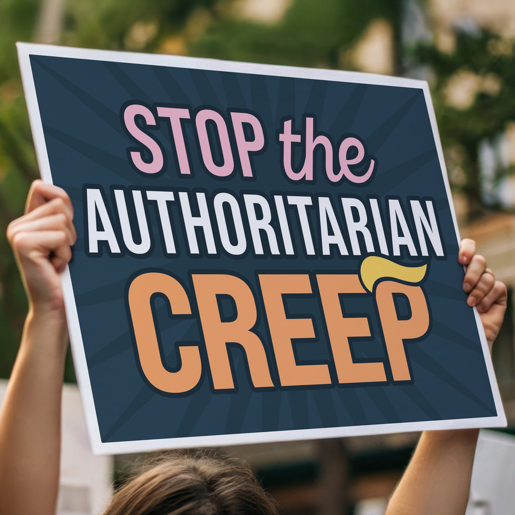 Person holding protest sign high in a crowd with the phrase "Stop the Authoritarian Creep" in bold lettering, featuring a yellow hairpiece resembling Trump’s weird hair on the last letter of the word “Creep,” emphasizing the double meaning of the sign.