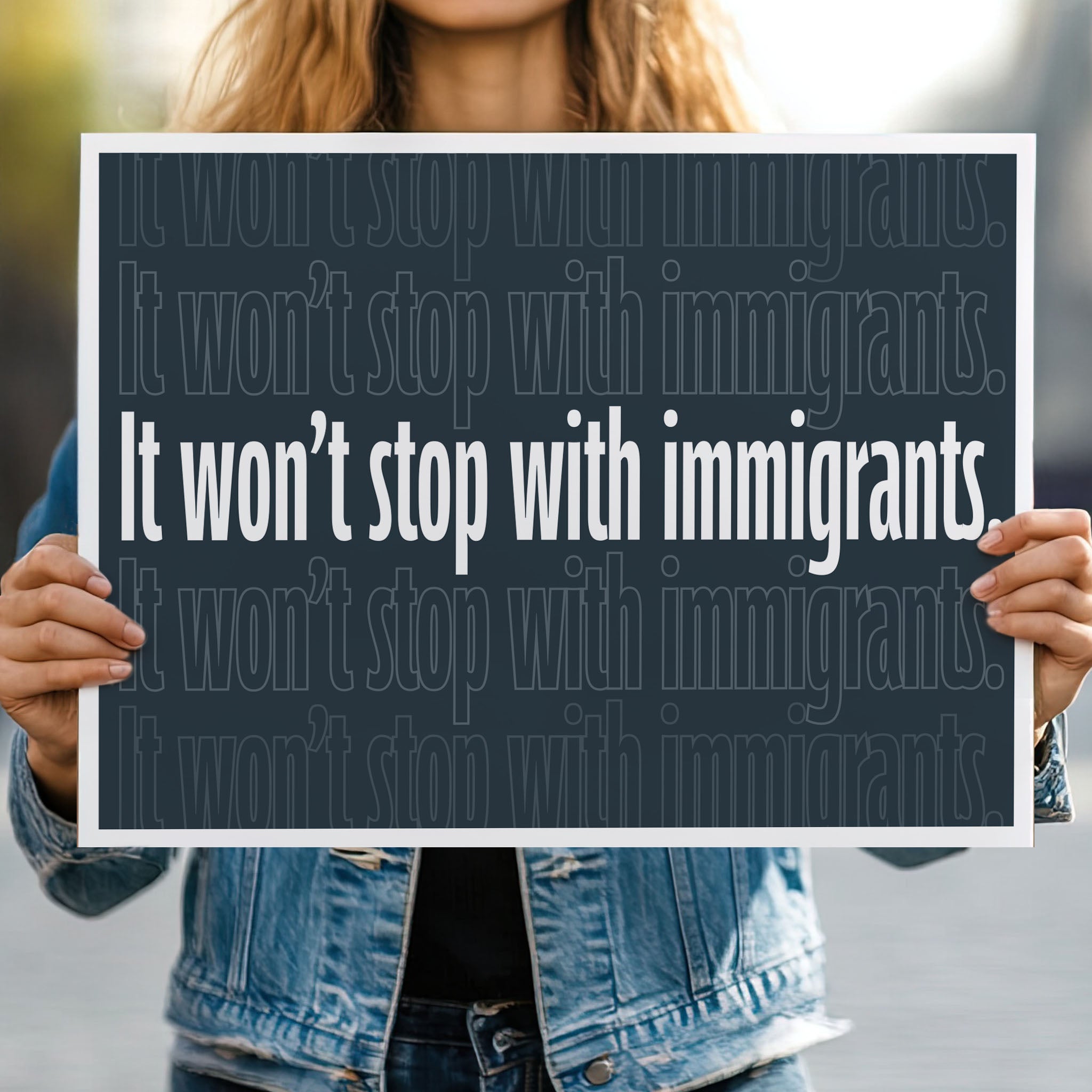 Person holding protest sign with dark background that reads "it won't stop with immigrants" in white in the center, with the same text repeated above and below but lighter and outlined.