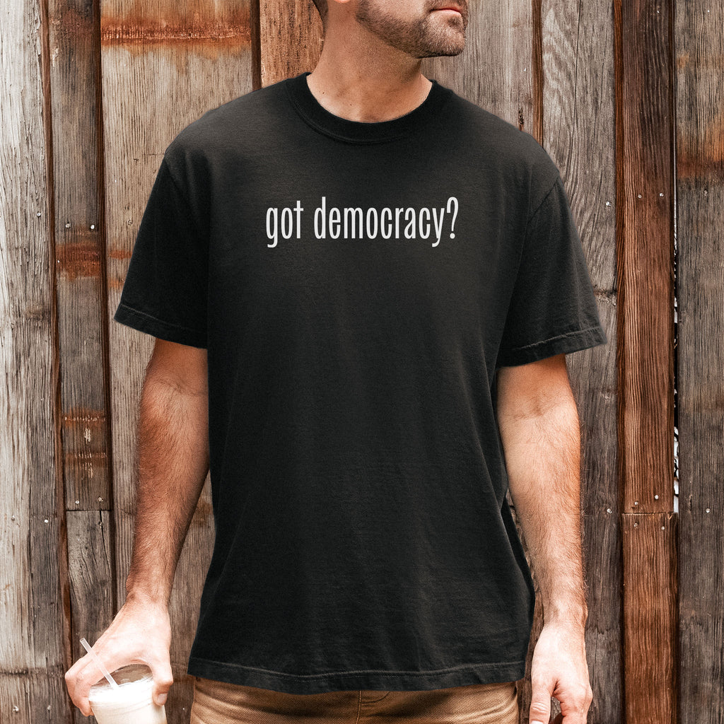 Male model wearing black t-shirt with white text reading “got democracy?” in minimalist font, styled like the classic “got milk?” campaign design.