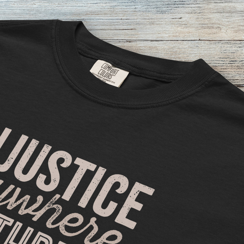Closeup detail of black t-shirt with bold text reading “Injustice anywhere is a threat to justice everywhere” quote from Martin Luther King Jr, MLK Jr, Letters from Birmingham jail — civil rights protest apparel for activists.