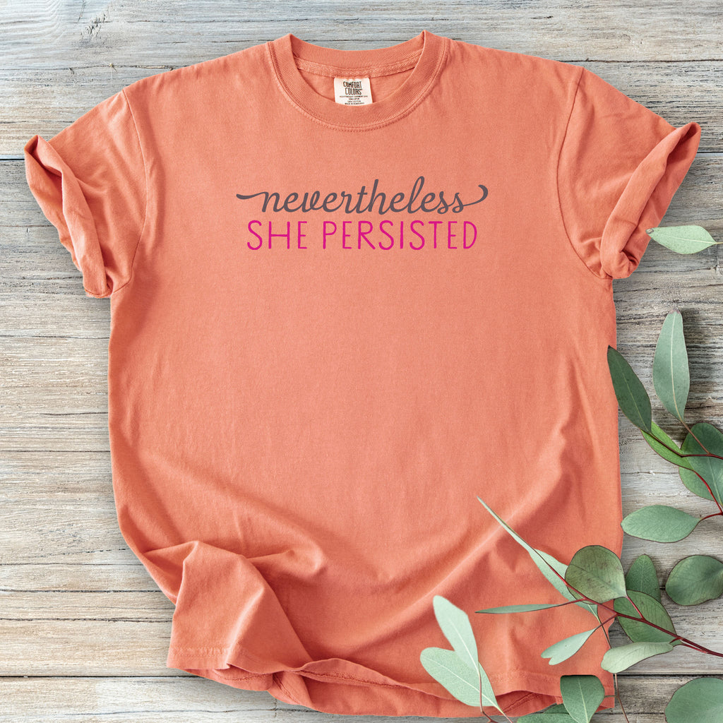 Terracotta orange Comfort Colors garment-dyed tee with stylized text graphic that reads "nevertheless she persisted."