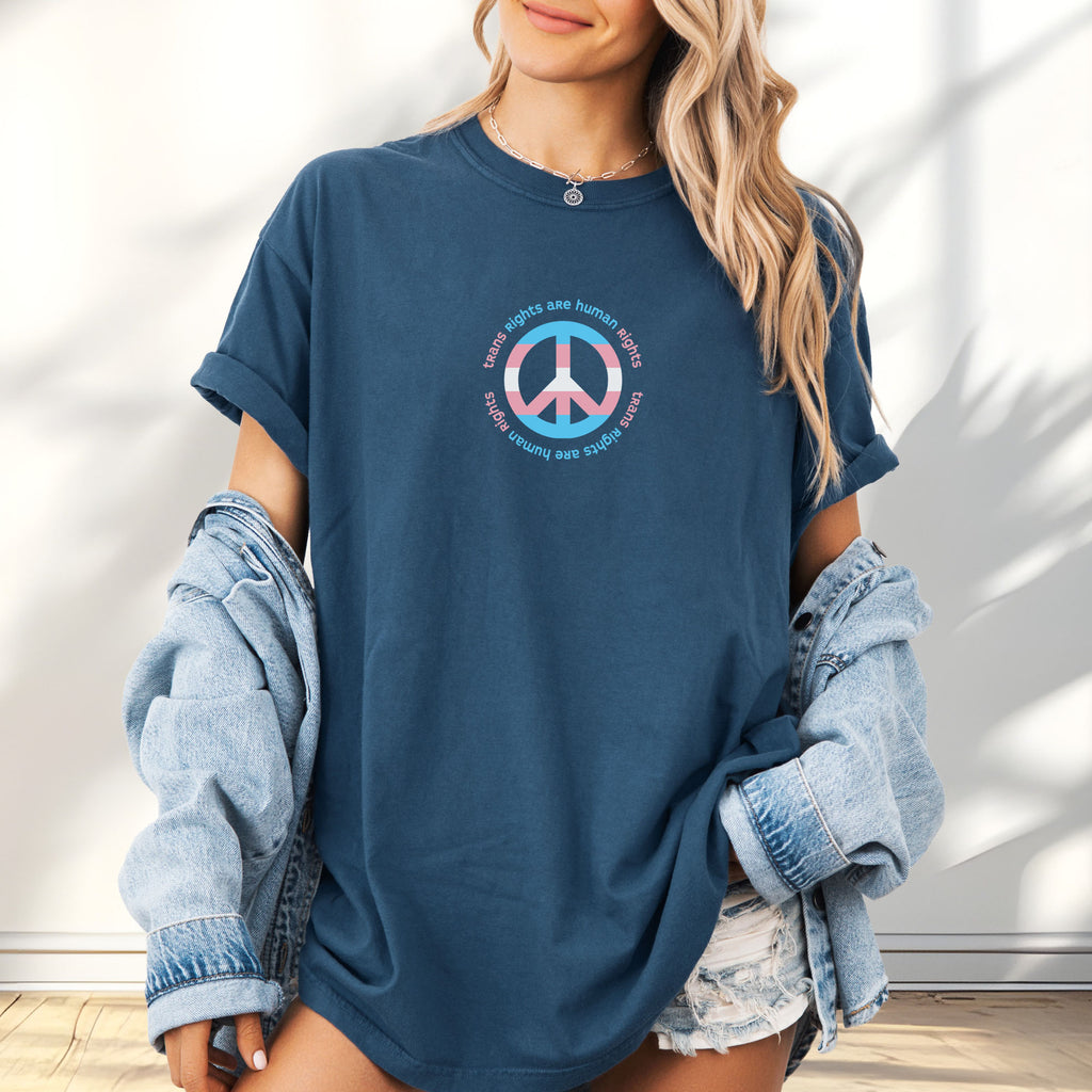 Female model wearing oversized midnight t-shirt with a peace sign in transgender flag colors and the text “Trans Rights Are Human Rights” in a circular design.