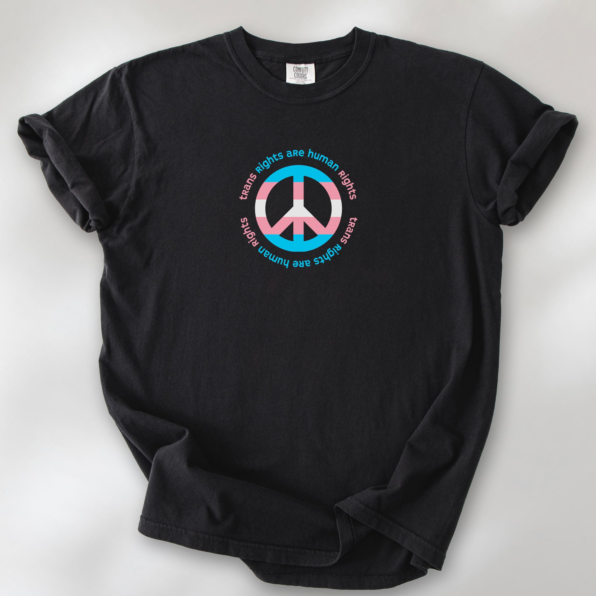 Black t-shirt with a peace sign in transgender flag colors and the text “Trans Rights Are Human Rights” in a circular design.