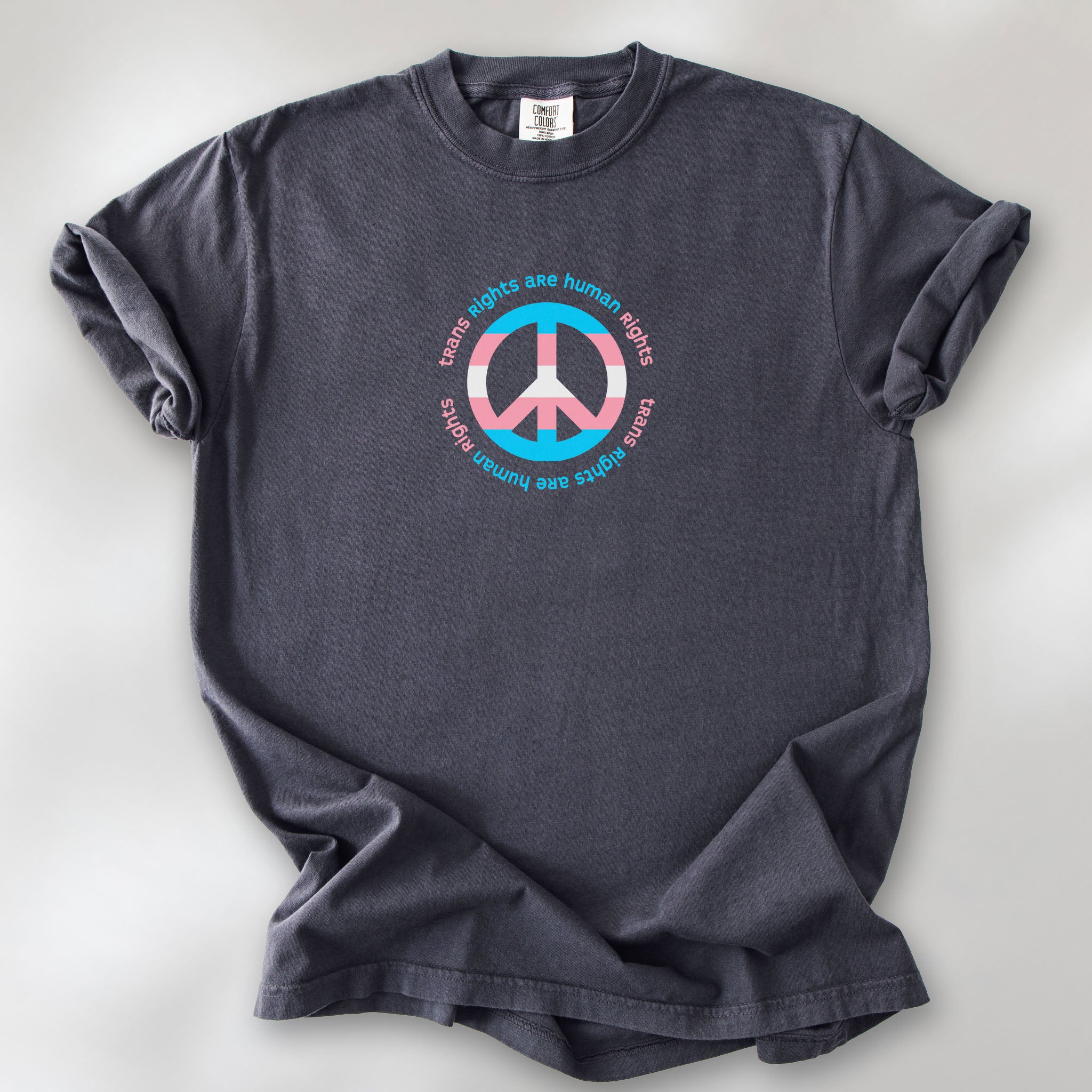 Graphite t-shirt with a peace sign in transgender flag colors and the text “Trans Rights Are Human Rights” in a circular design.