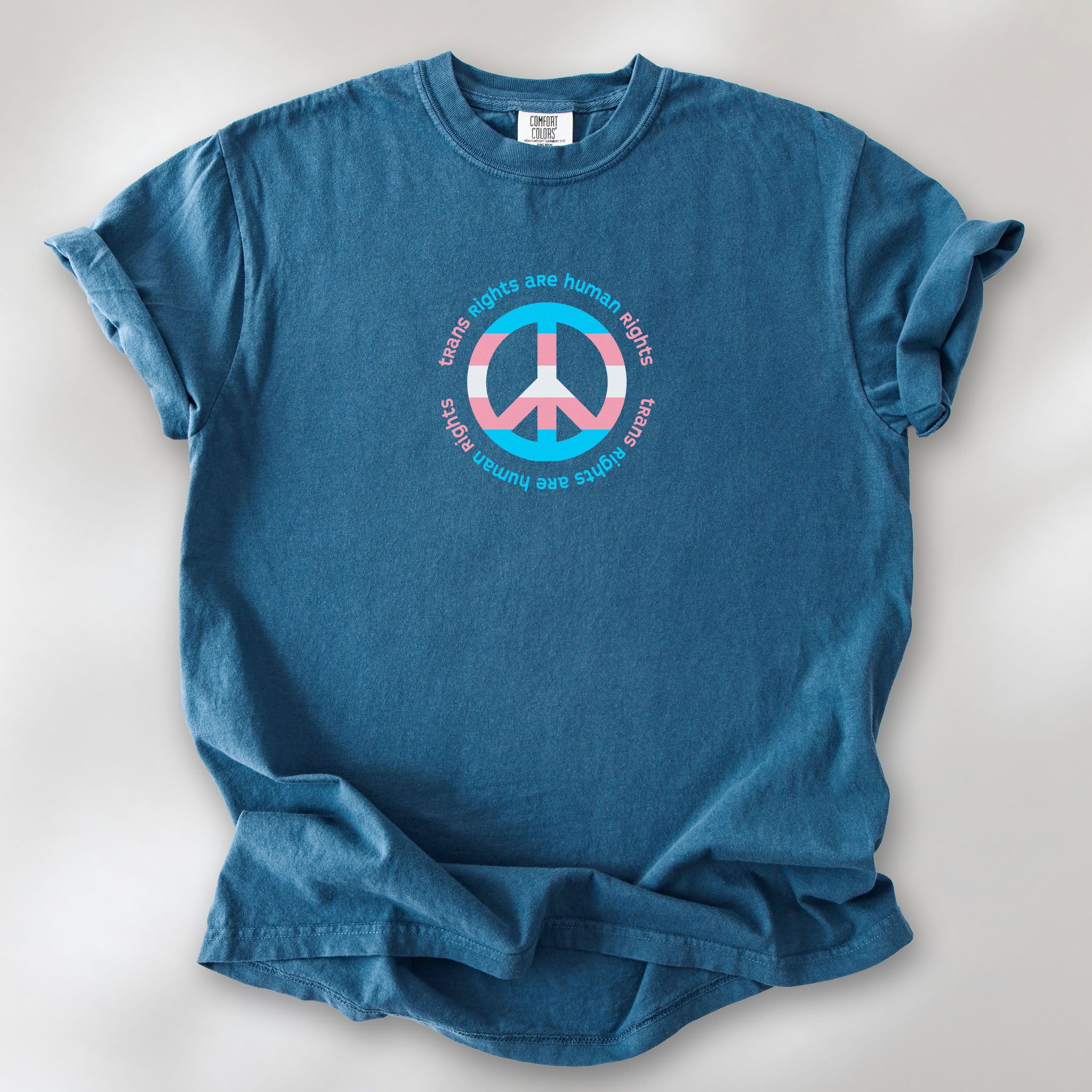 Midnight t-shirt with a peace sign in transgender flag colors and the text “Trans Rights Are Human Rights” in a circular design.