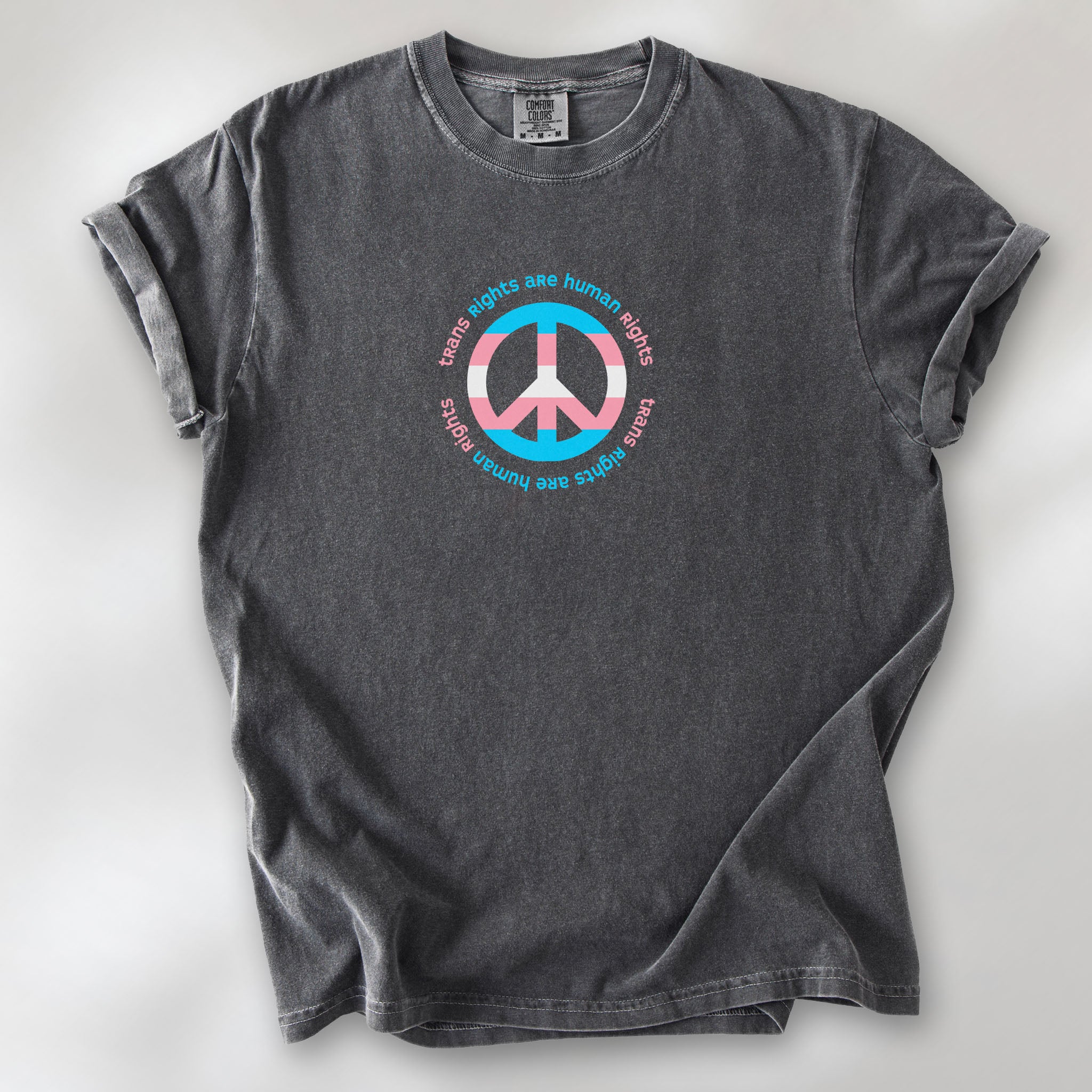 Pepper t-shirt with a peace sign in transgender flag colors and the text “Trans Rights Are Human Rights” in a circular design.