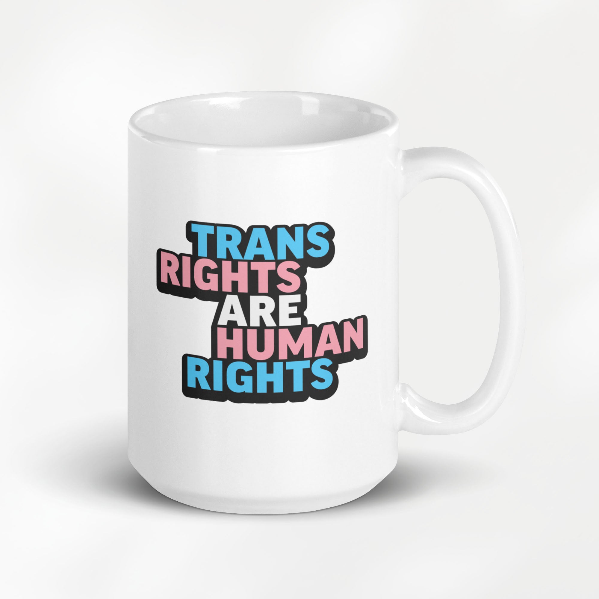15 ounce white ceramic mug with bold text “Trans Rights Are Human Rights” in blue, pink, and black colors representing the transgender pride flag.