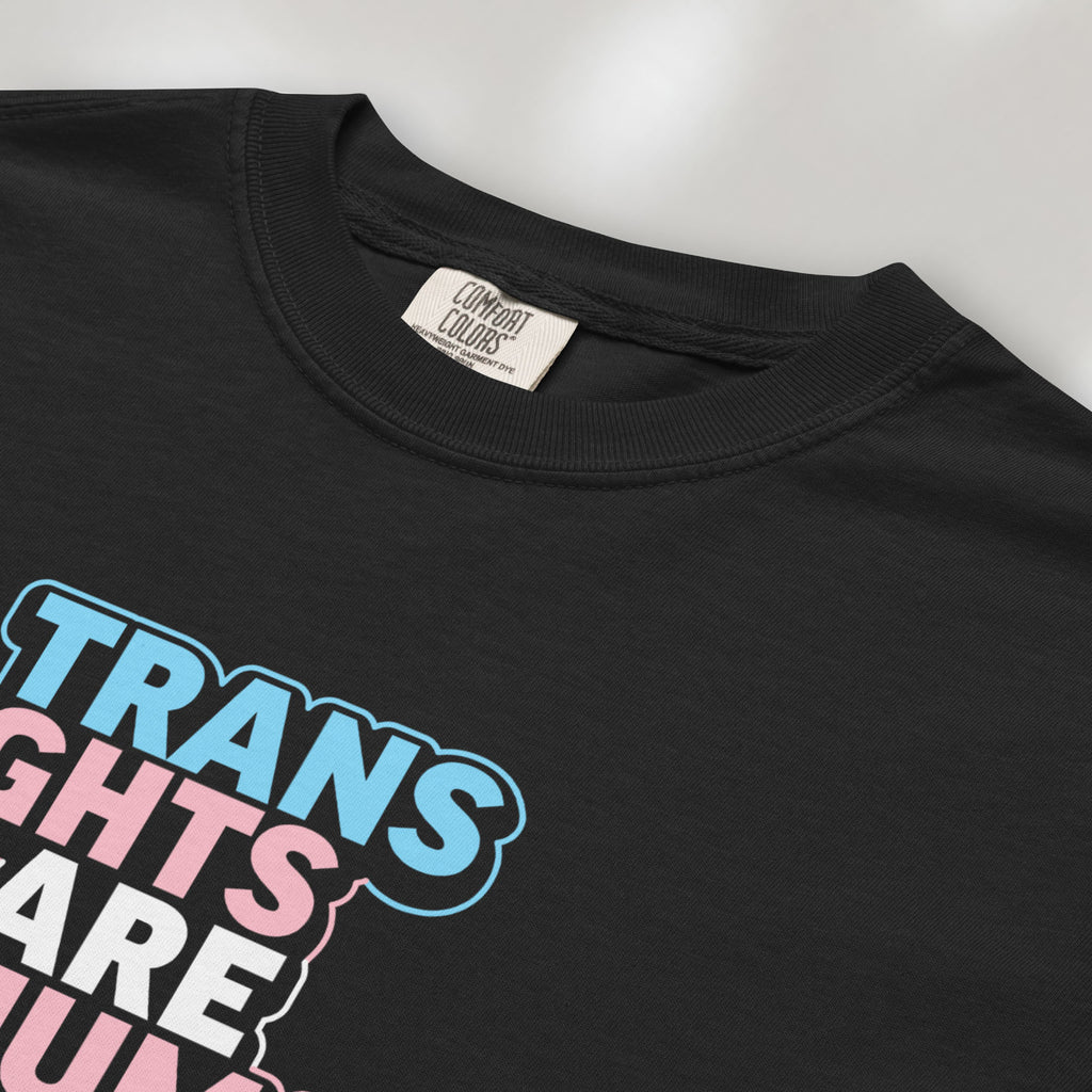 Closeup detail of black t-shirt with graphic reading "trans rights are human rights" in the colors of the trans flag.