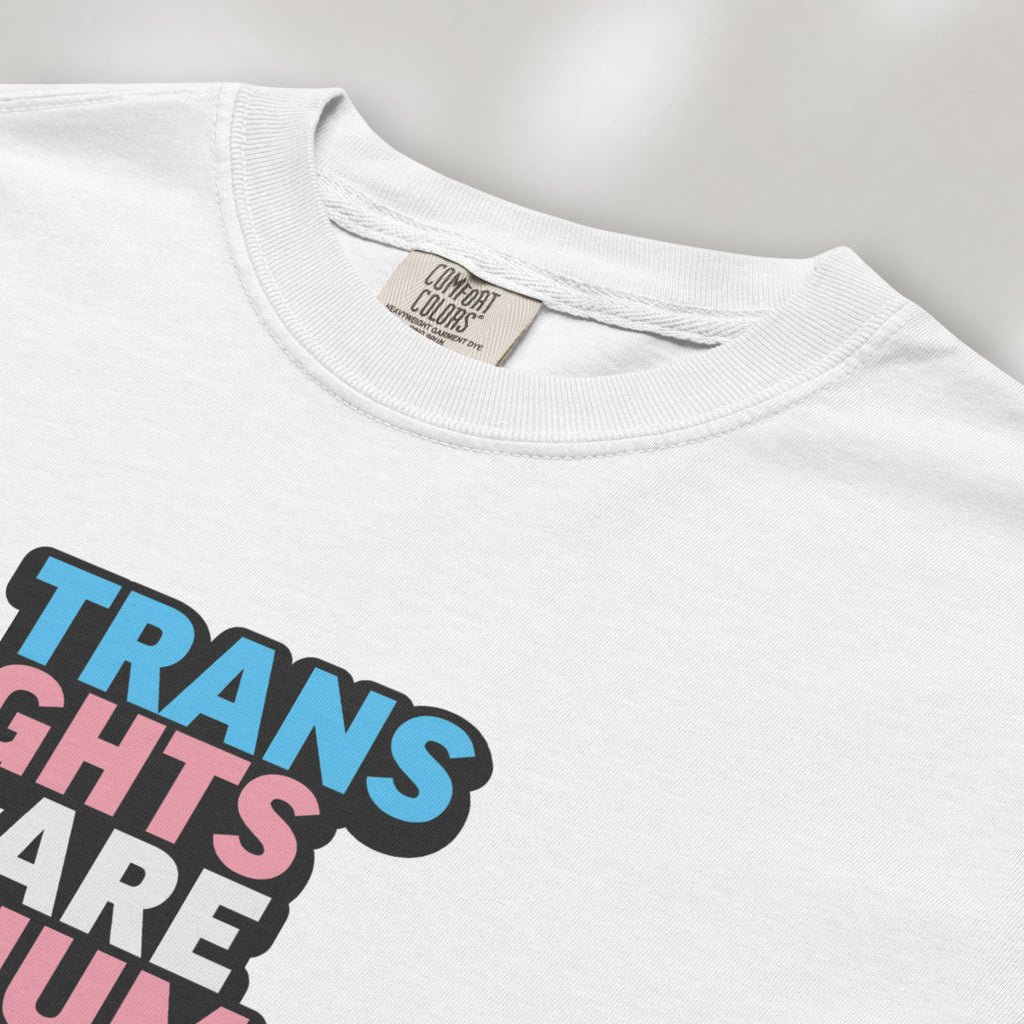 Closeup detail of white t-shirt with graphic reading "trans rights are human rights" in the colors of the trans flag.