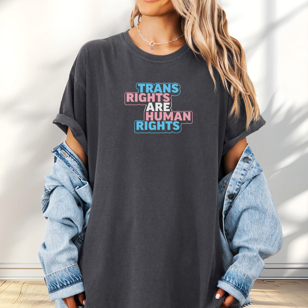 Female model wearing pepper t-shirt with graphic reading "trans rights are human rights" in the colors of the trans flag.