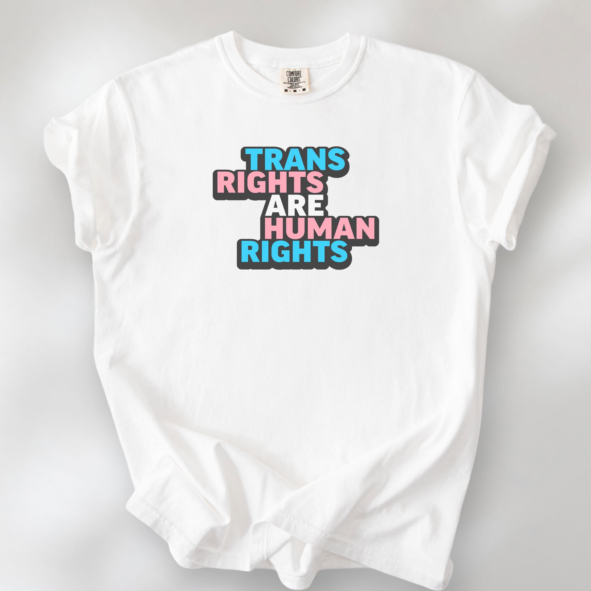 White t-shirt with graphic reading "trans rights are human rights" in the colors of the trans flag.