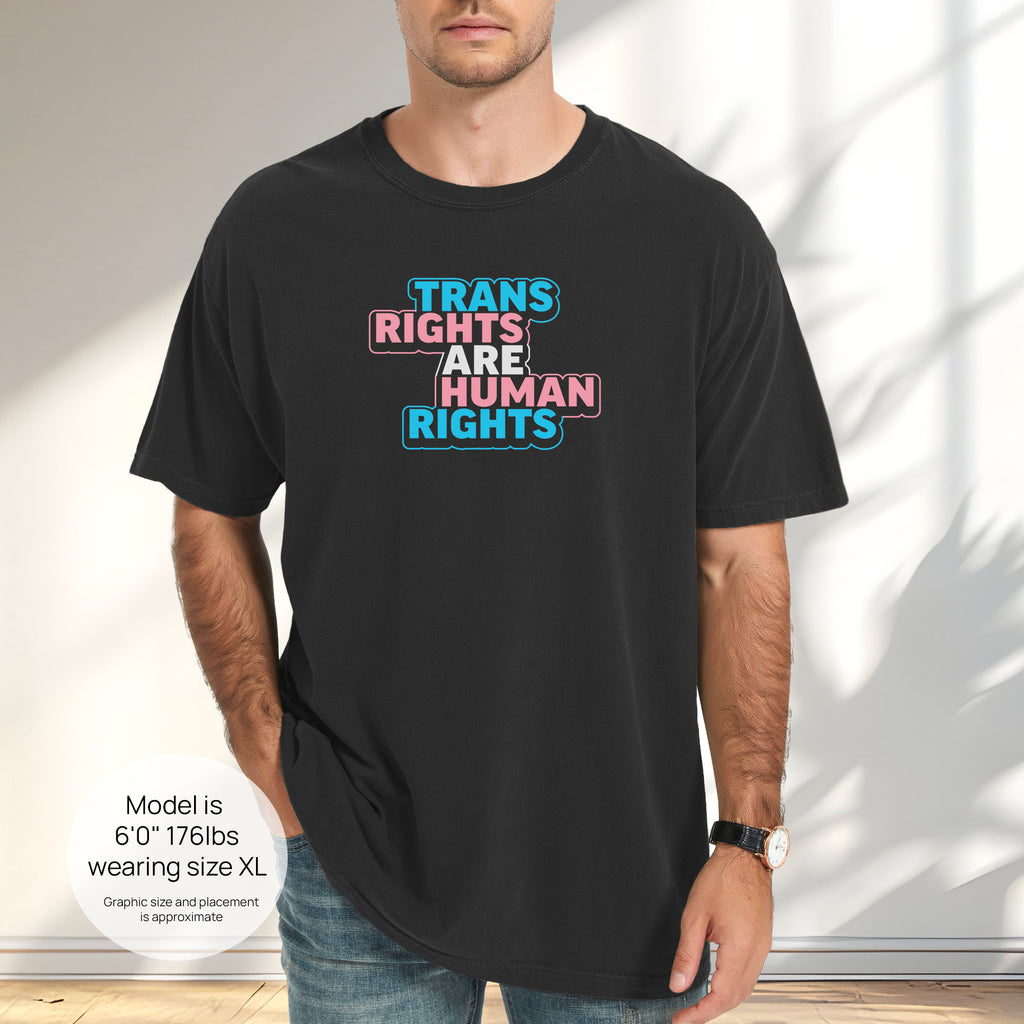 Male model wearing black t-shirt with graphic reading "trans rights are human rights" in the colors of the trans flag. Includes size and fit information for the model who is 6 feet 0 inches, 176 pounds, and wearing a size XL shirt.
