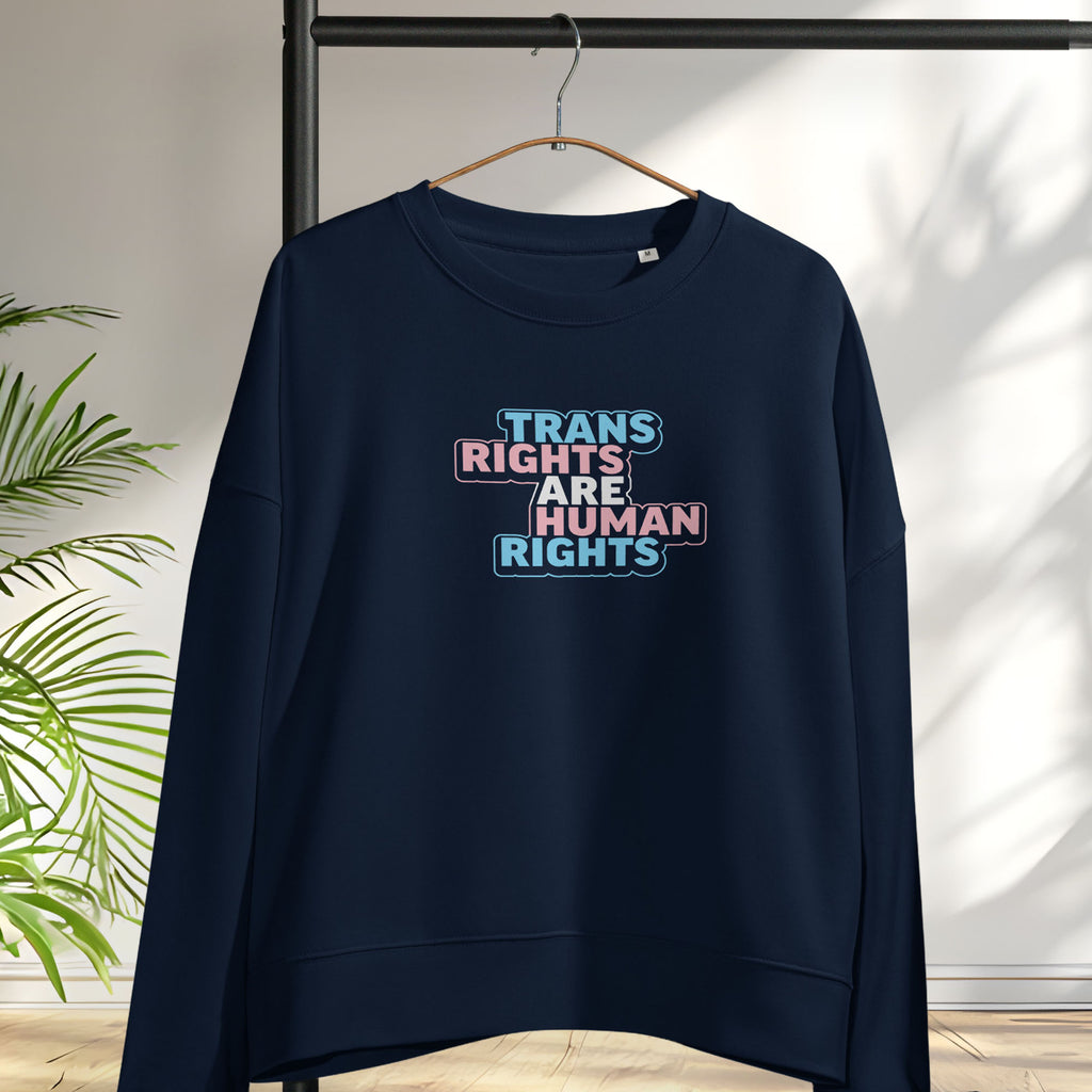 Hanging navy women's crewneck sweatshirt with graphic that reads "trans rights are human rights" in the light blue, pink, and white colors of the trans flag.