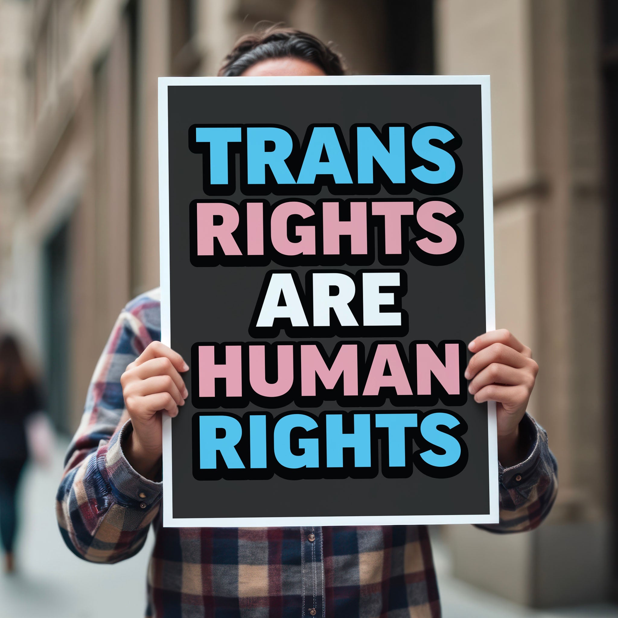Person holding protest sign that reads “Trans Rights Are Human Rights” in blue, pink, and white lettering, symbolizing support for transgender equality and resistance to discrimination under the Trump administration.