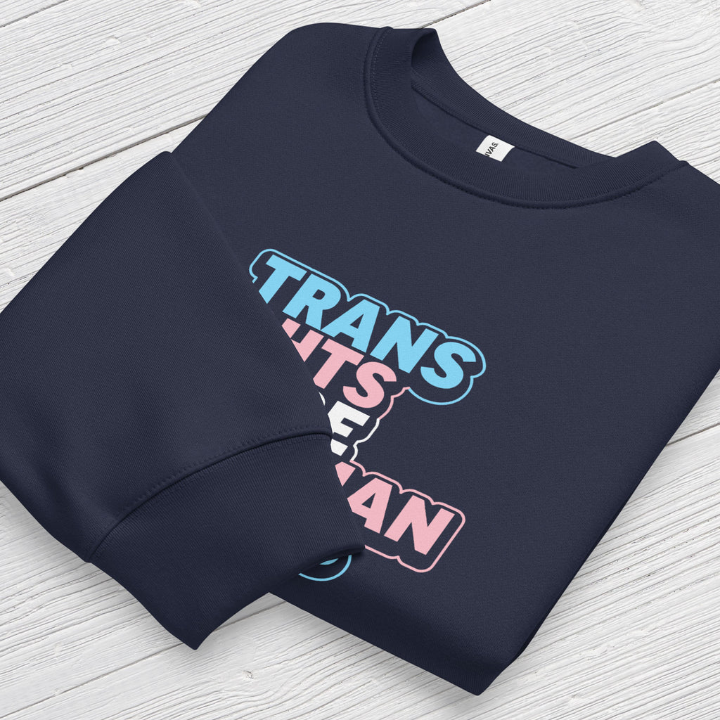 Folded navy crewneck sweatshirt with graphic that reads "trans rights are human rights" in the light blue, pink, and white colors of the trans flag, with a colorful outline around the text block.