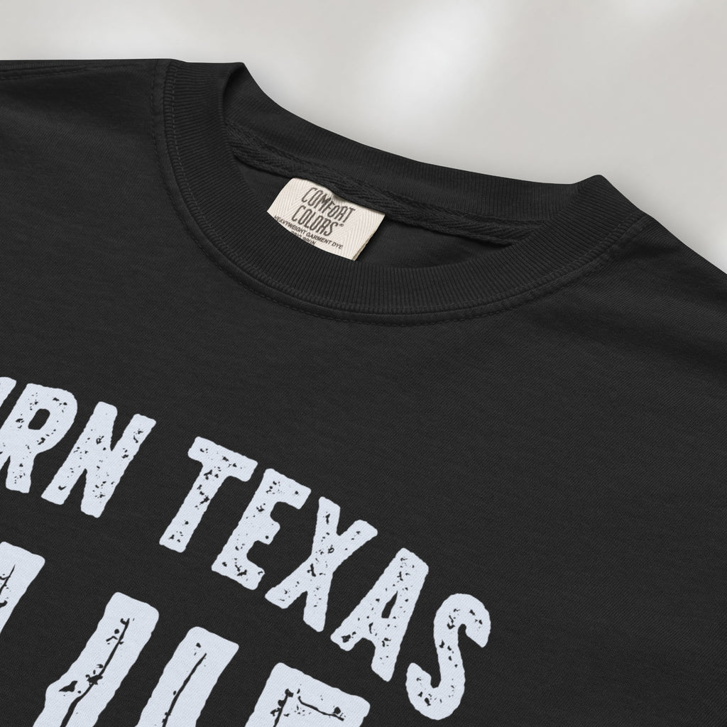 Closeup detail of black t-shirt featuring distressed "Turn Texas Blue" text with a small Texas icon and the phrase "Show Up Be Heard."