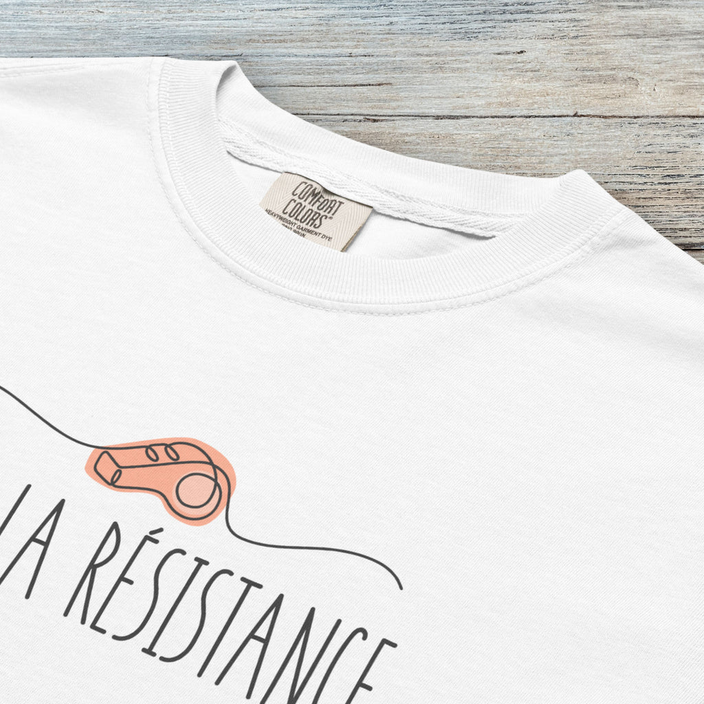 Closeup detail of white unisex t-shirt reading “Viva La Resistance” with a whistle illustration referencing community alert systems used to warn neighbors of ICE presence.