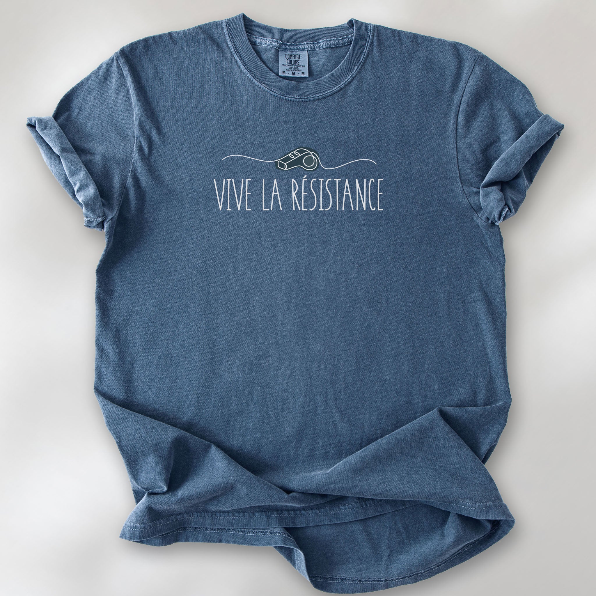 Denim unisex t-shirt reading “Vive La Resistance” with a whistle illustration referencing community alert systems used to warn neighbors of ICE presence.