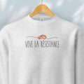 Hanging grey sweatshirt reading “Viva La Resistance” with a whistle illustration referencing community alert systems used to warn neighbors of ICE presence.