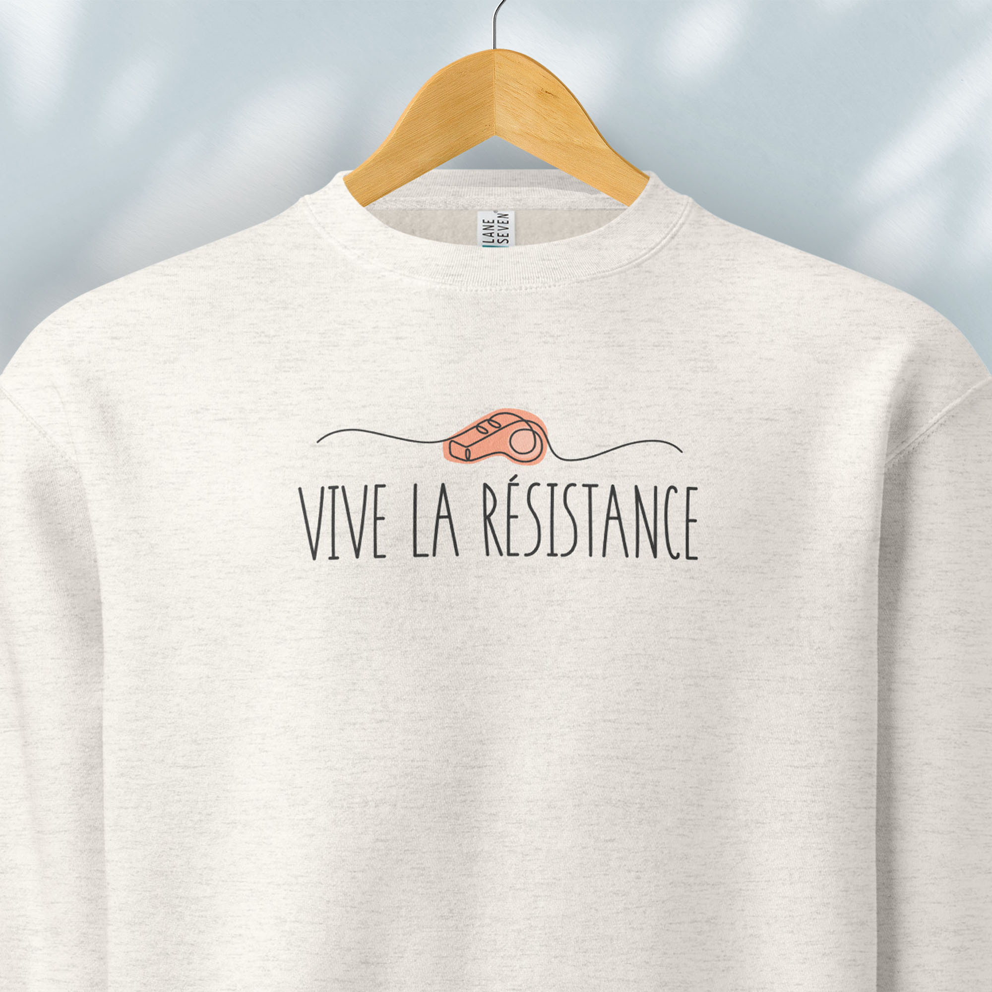 Hanging oatmeal sweatshirt reading “Viva La Resistance” with a whistle illustration referencing community alert systems used to warn neighbors of ICE presence.
