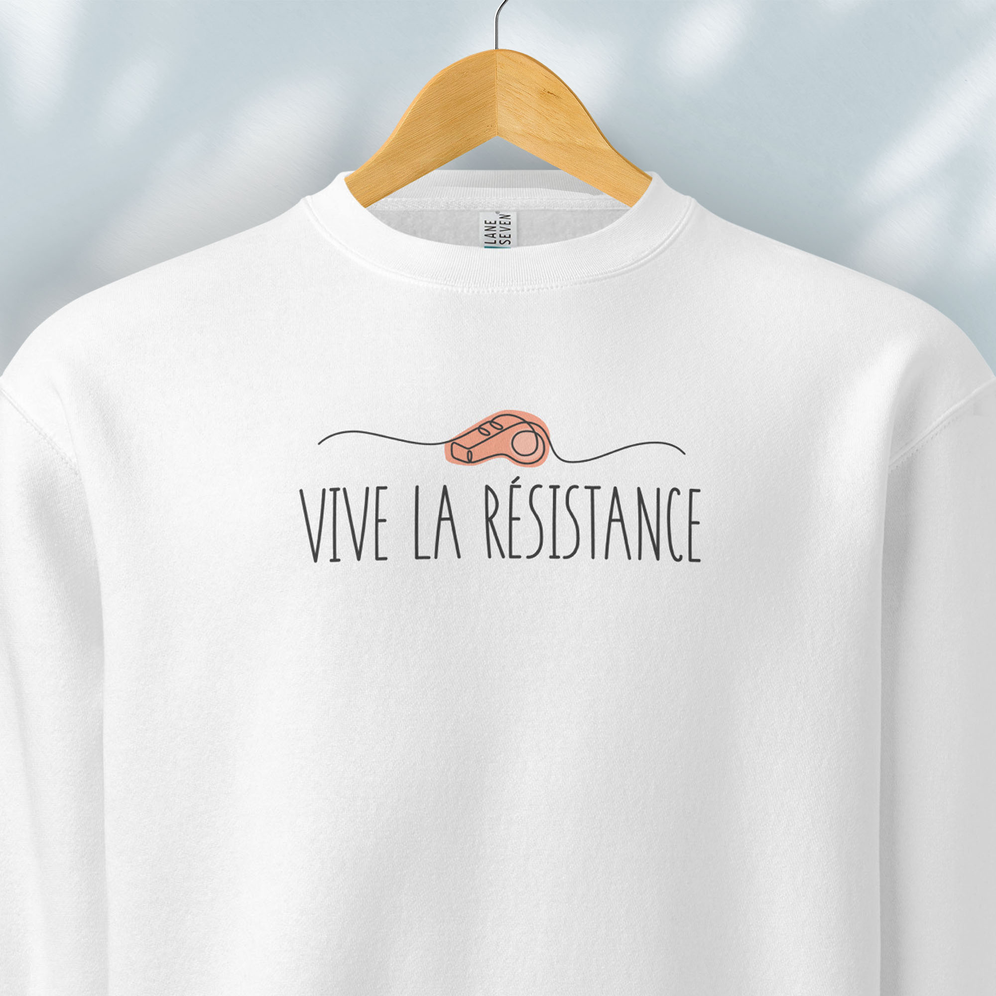 Hanging white sweatshirt reading “Viva La Resistance” with a whistle illustration referencing community alert systems used to warn neighbors of ICE presence.