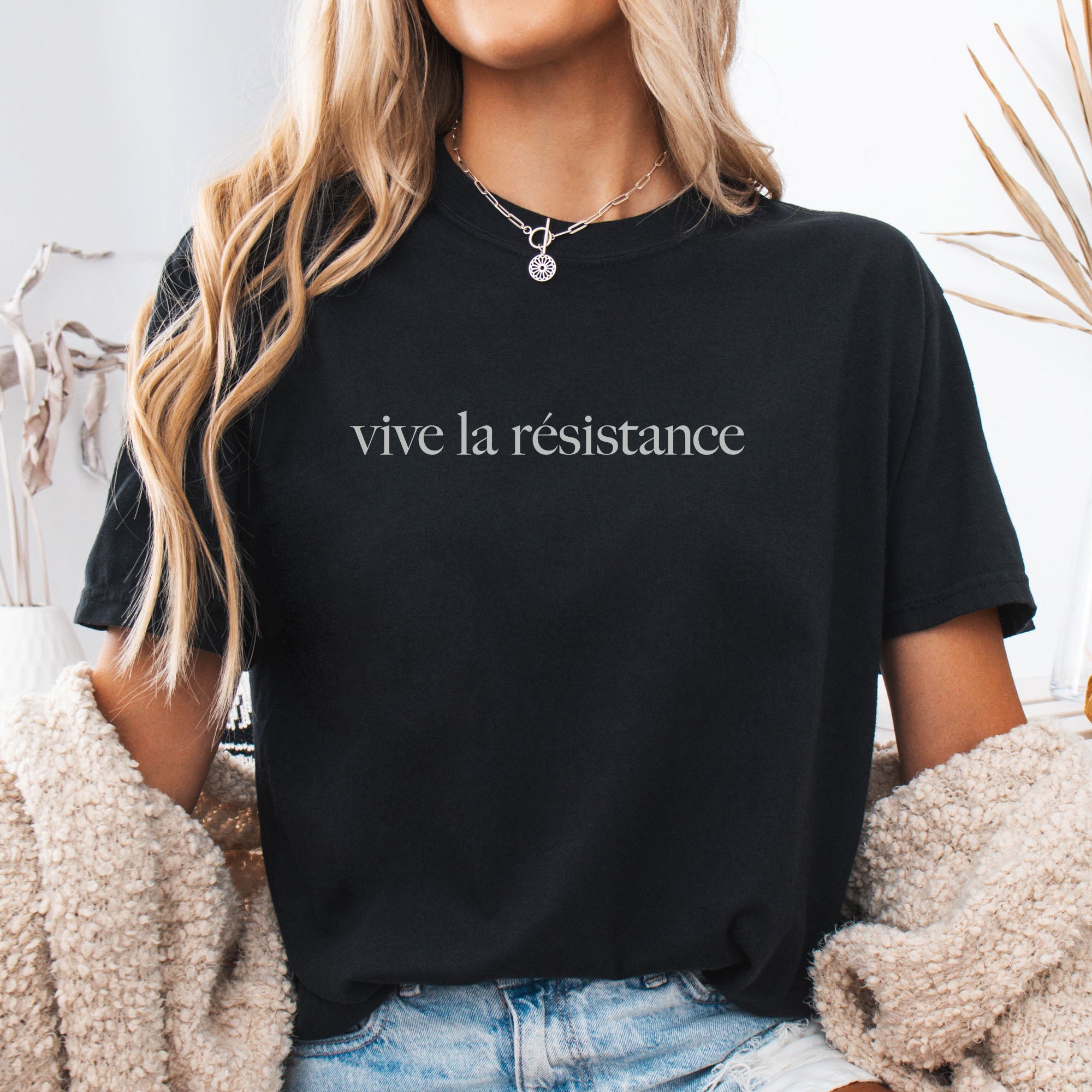 Female model wearing black t-shirt with minimalist serif text reading “vive la résistance.”