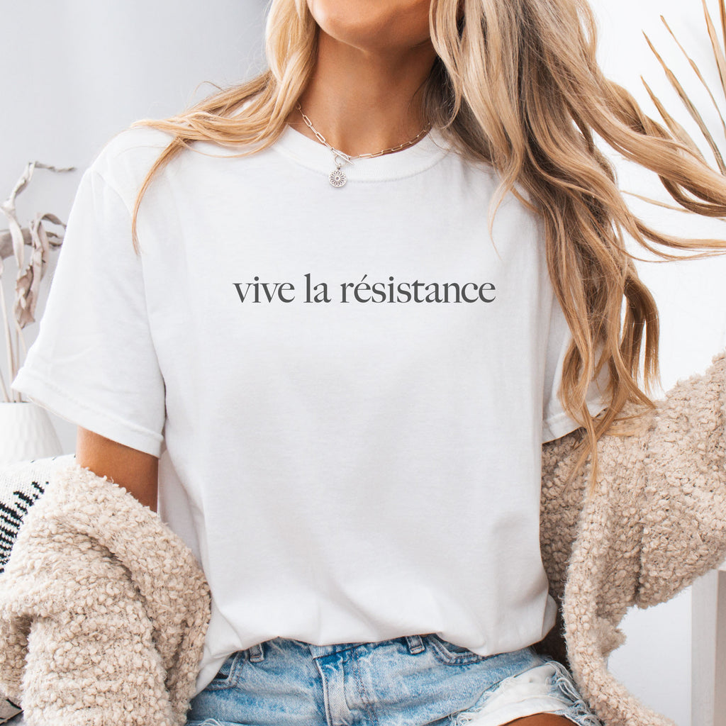 Female model wearing white t-shirt with minimalist serif text reading “vive la résistance.”