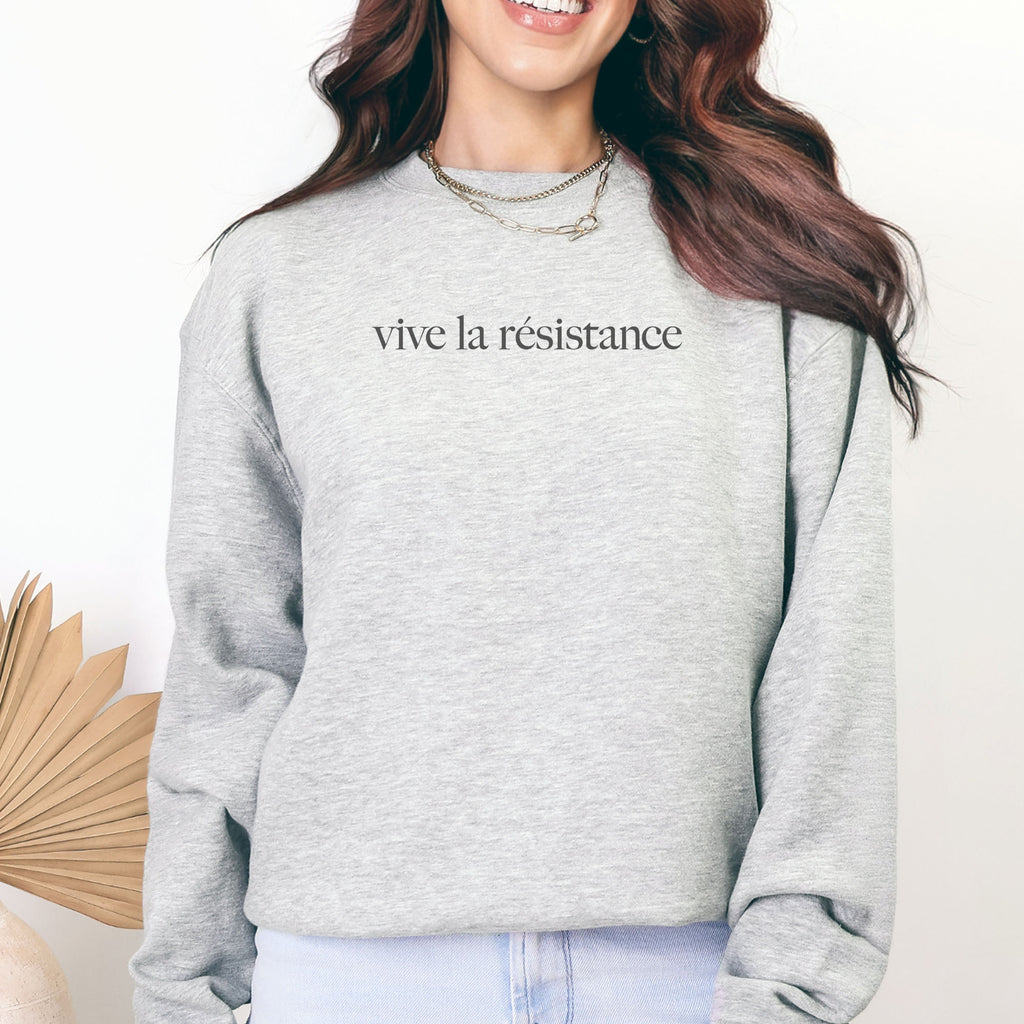 Female model wearing grey sweatshirt with minimalist serif text reading “vive la résistance.”