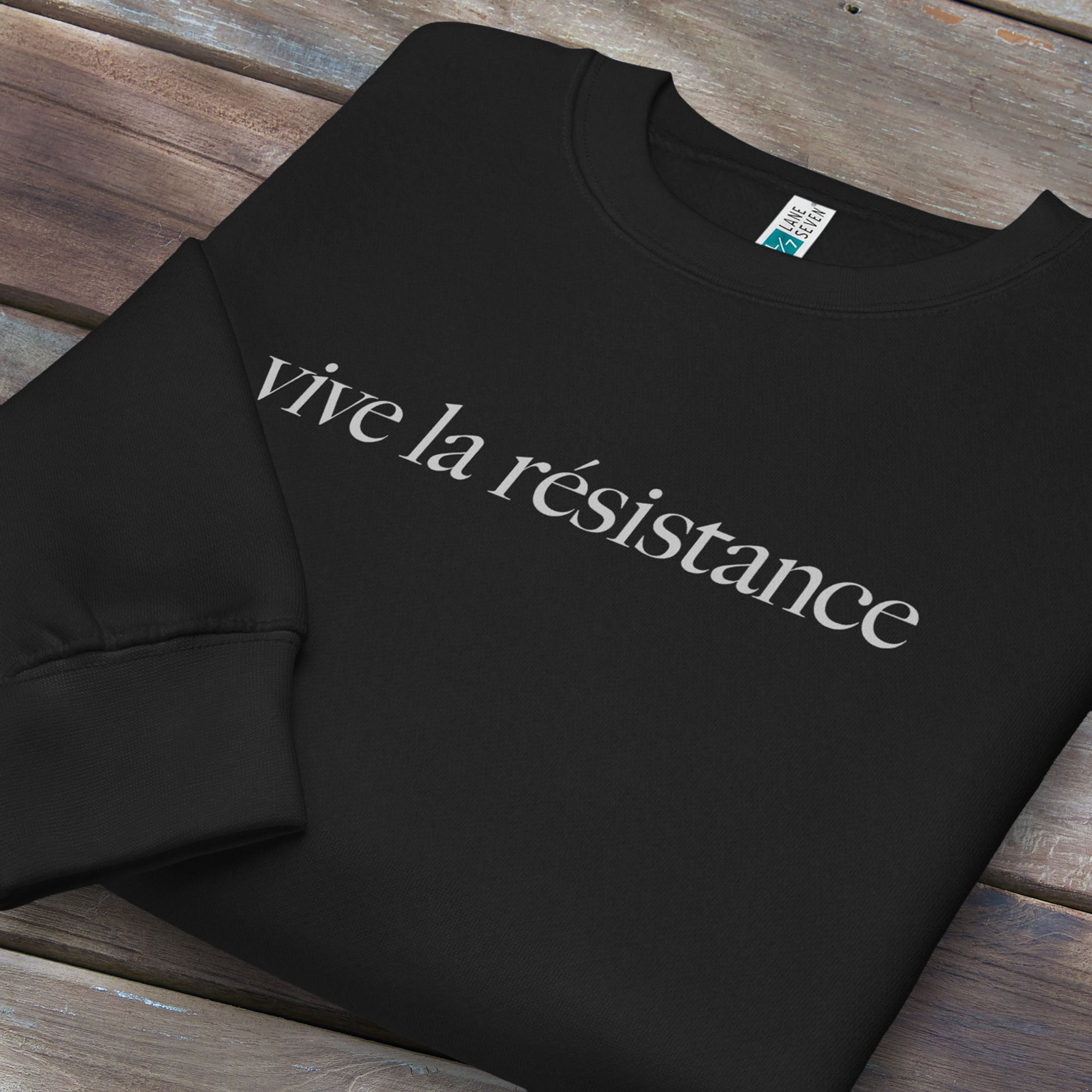 Folded black sweatshirt with minimalist serif text reading “vive la résistance.”