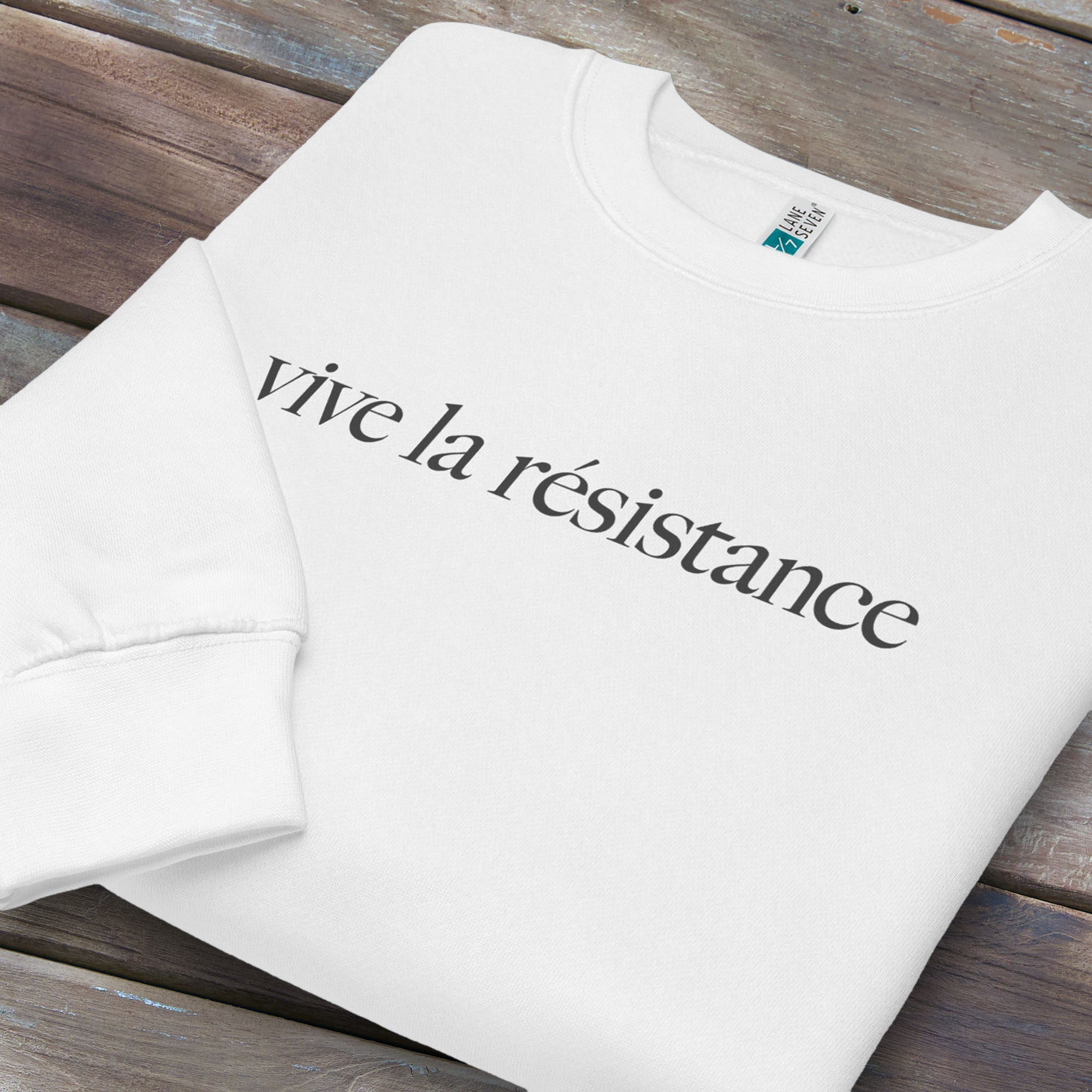 Folded white sweatshirt with minimalist serif text reading “vive la résistance.”