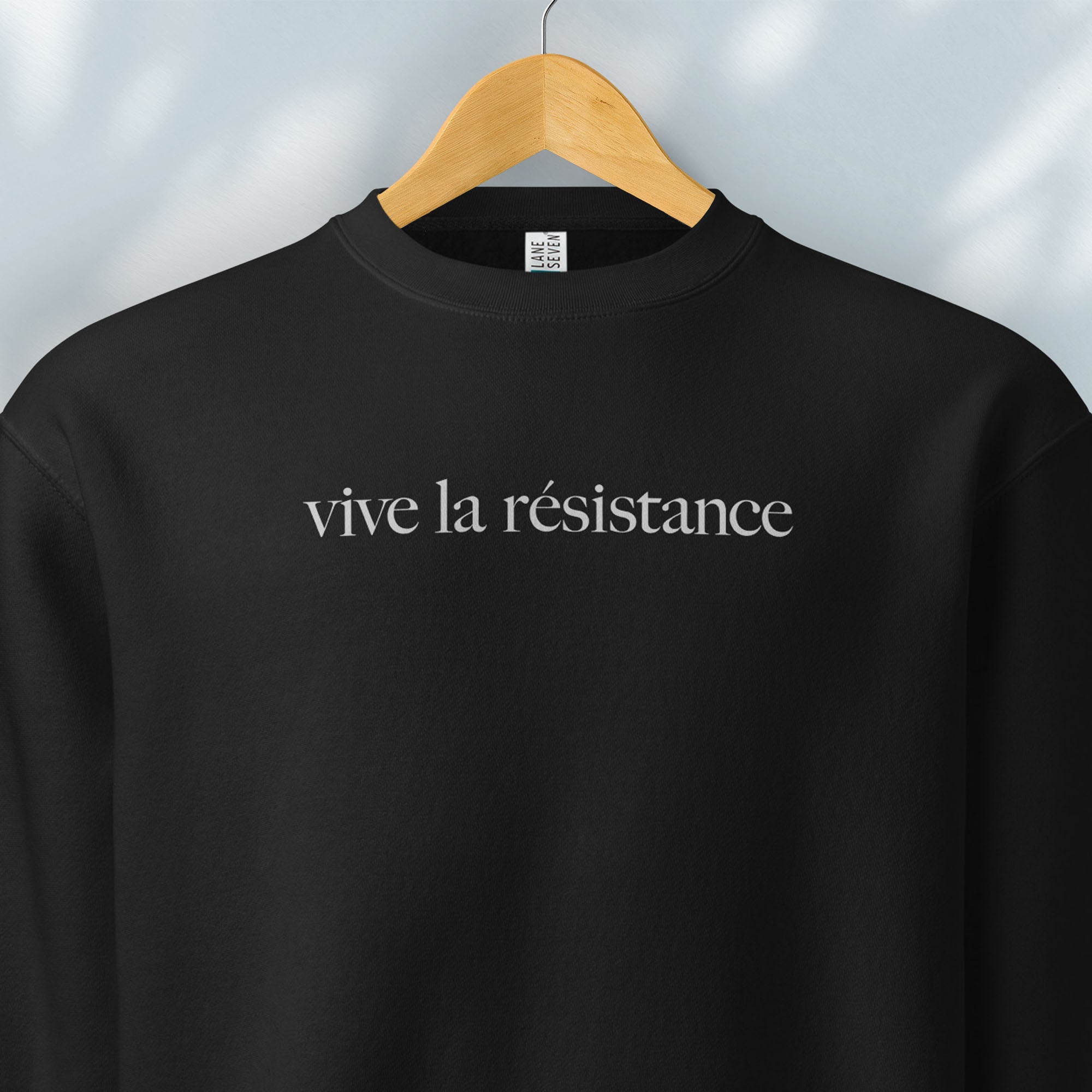 Hanging black sweatshirt with minimalist serif text reading “vive la résistance.”
