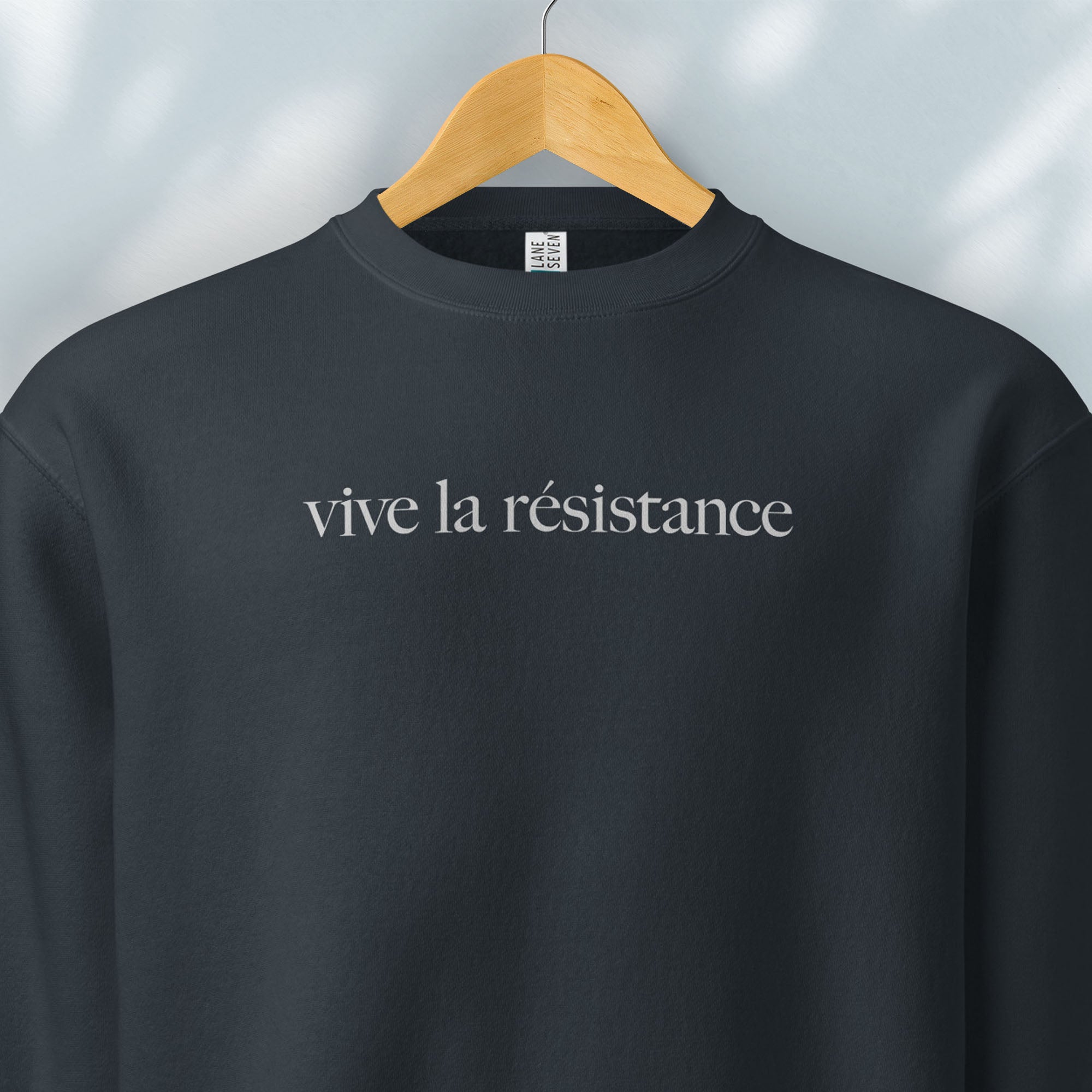 Hanging navy sweatshirt with minimalist serif text reading “vive la résistance.”