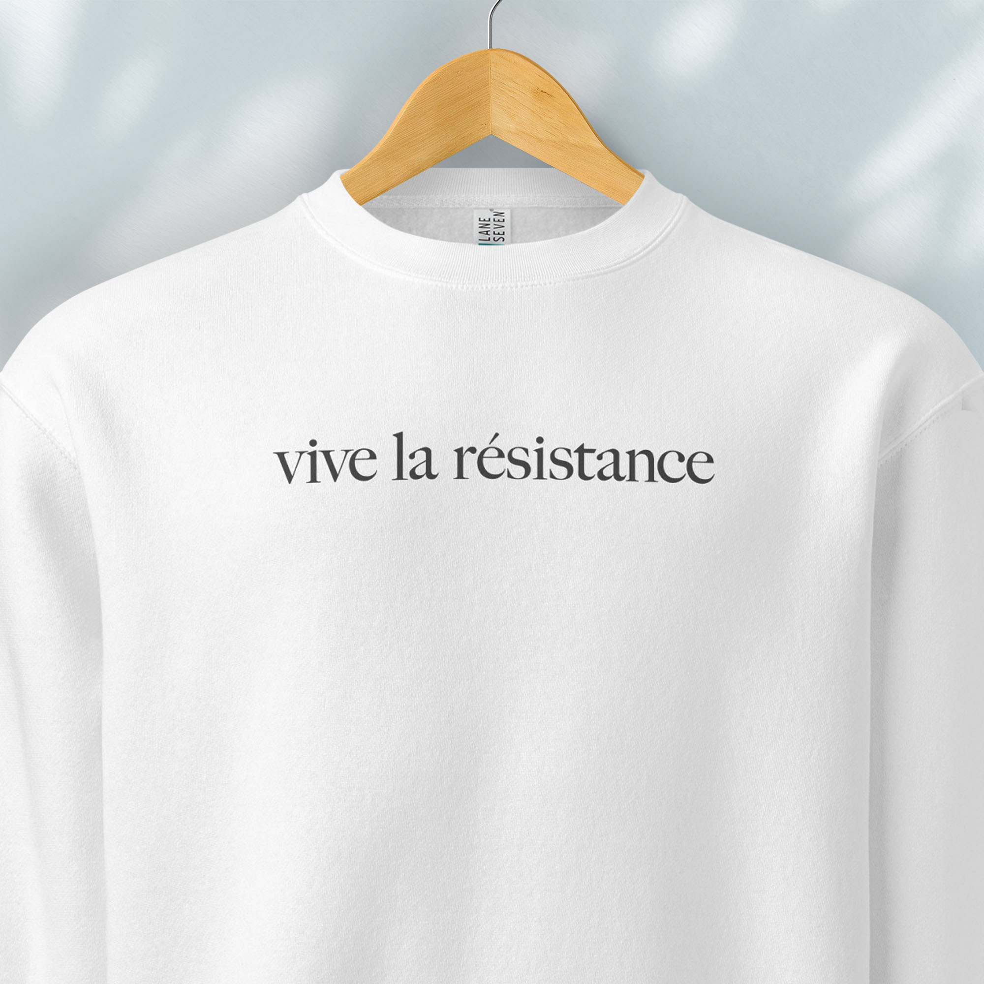 Hanging white sweatshirt with minimalist serif text reading “vive la résistance.”
