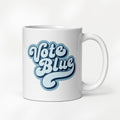11 ounce white ceramic coffee mug featuring a retro blue “Vote Blue” script design.