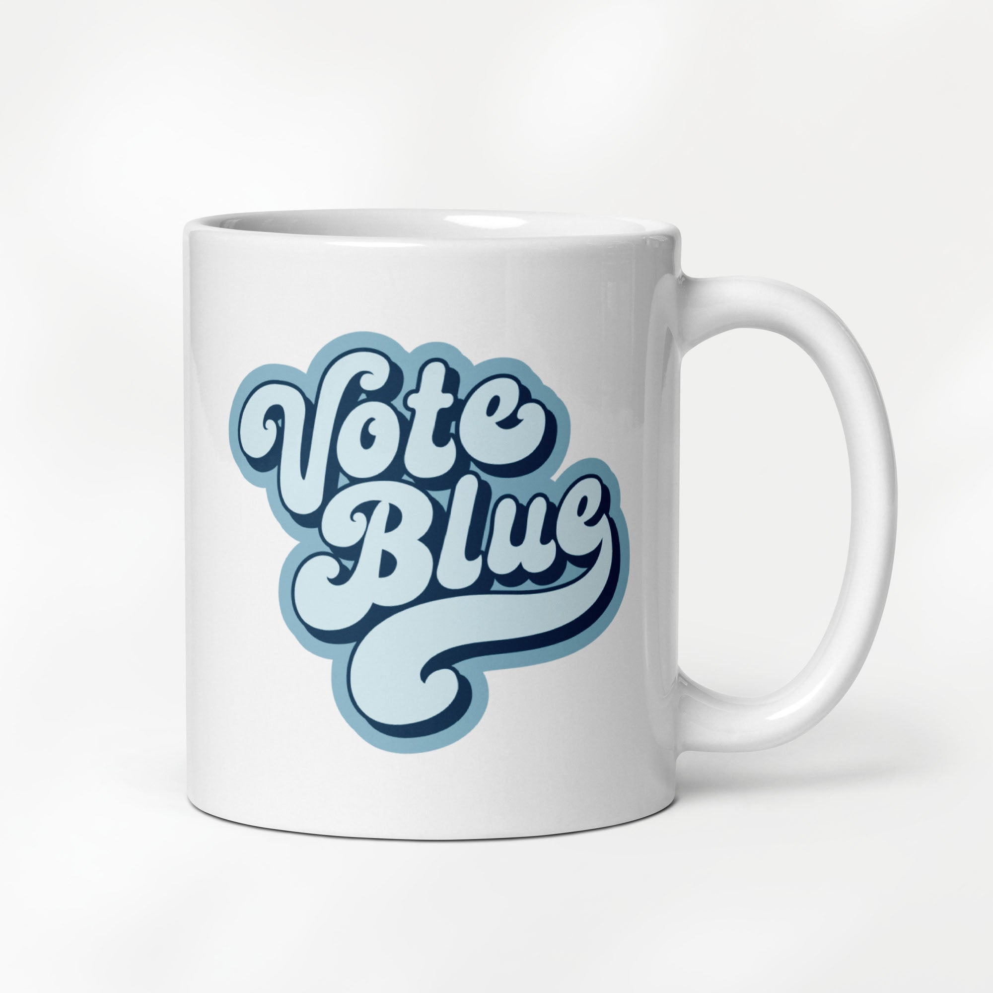 11 ounce white ceramic coffee mug featuring a retro blue “Vote Blue” script design.
