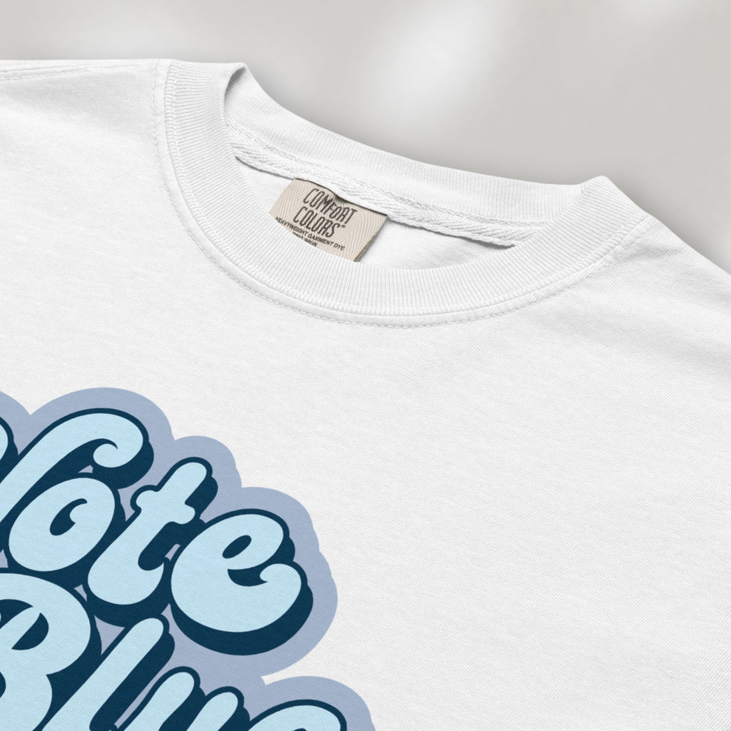 Closeup detail of white t-shirt featuring a retro blue "Vote Blue" script graphic.