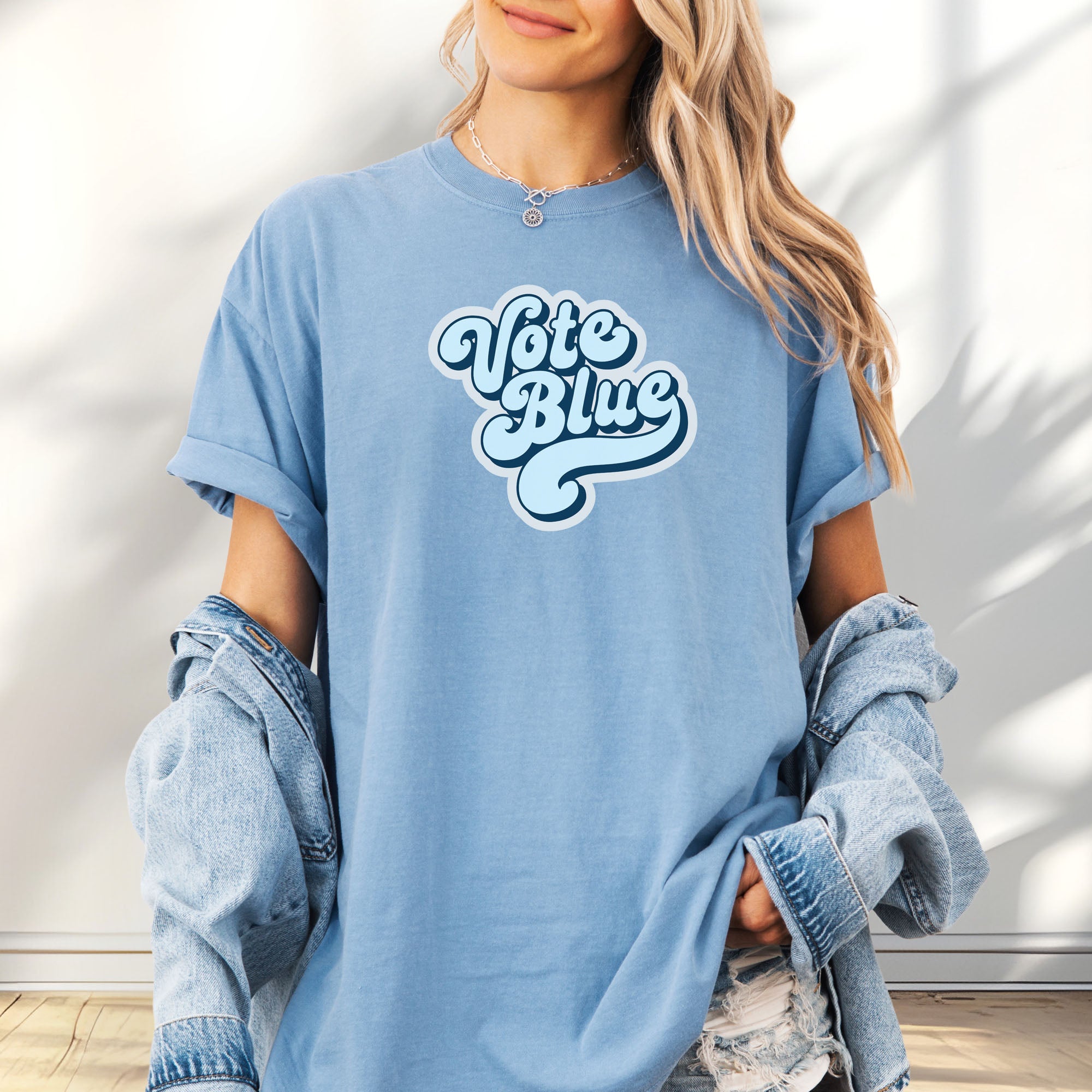 Female model wearing oversized washed denim t-shirt featuring a retro blue "Vote Blue" script graphic.