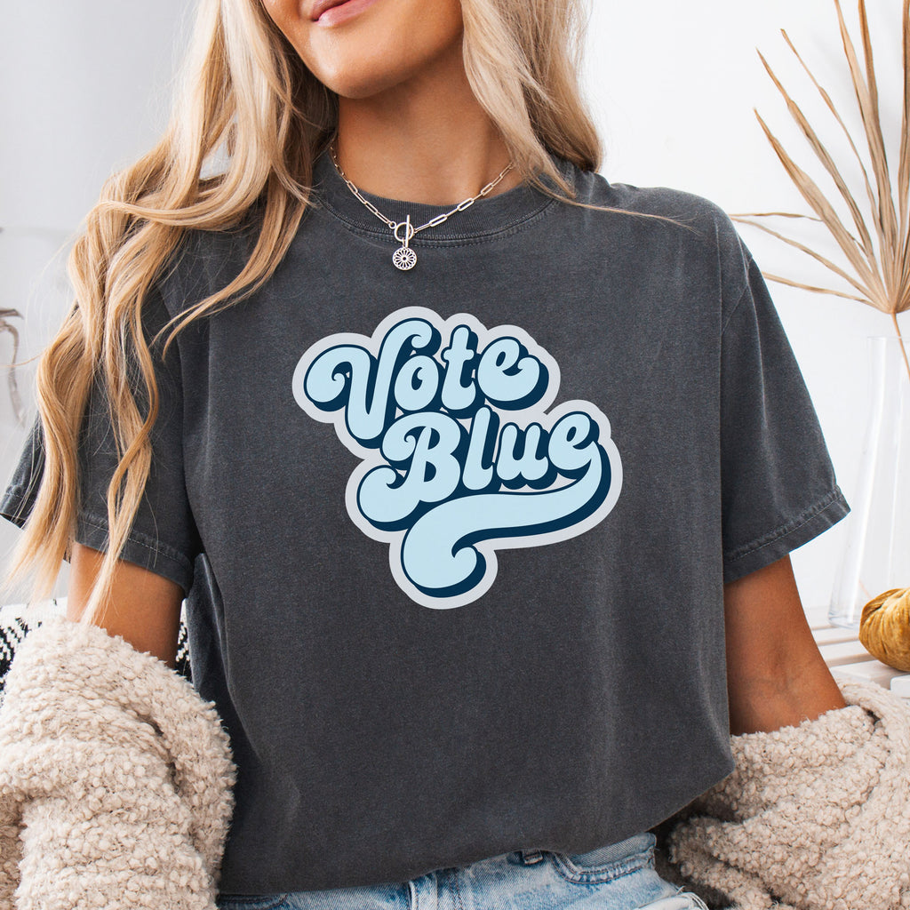 Female model wearing pepper t-shirt featuring a retro blue "Vote Blue" script graphic.