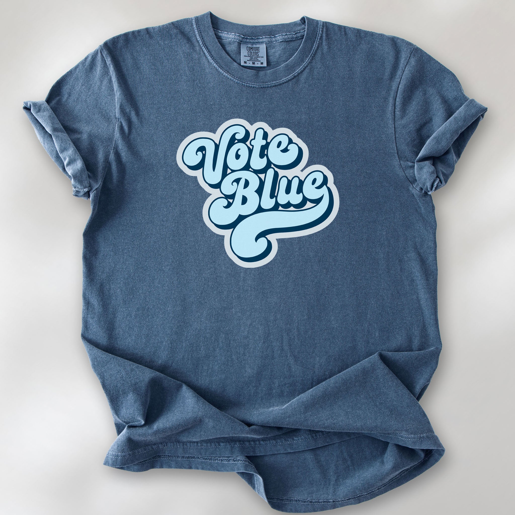 Denim t-shirt featuring a retro blue "Vote Blue" script graphic.