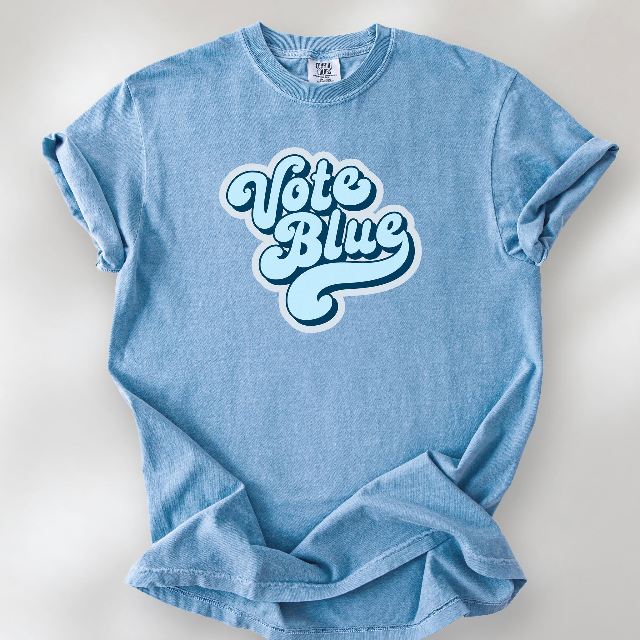 Washed denim t-shirt featuring a retro blue "Vote Blue" script graphic.