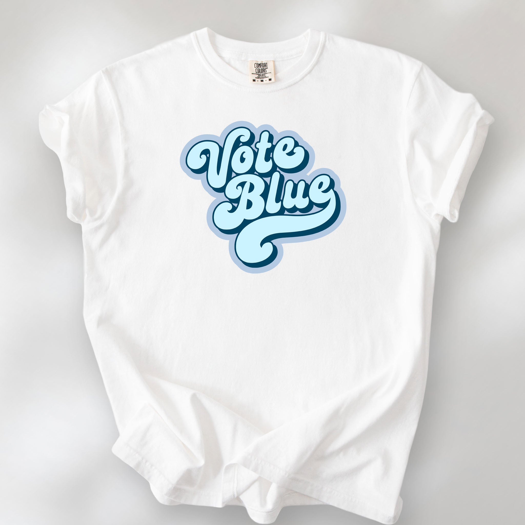 White t-shirt featuring a retro blue "Vote Blue" script graphic.