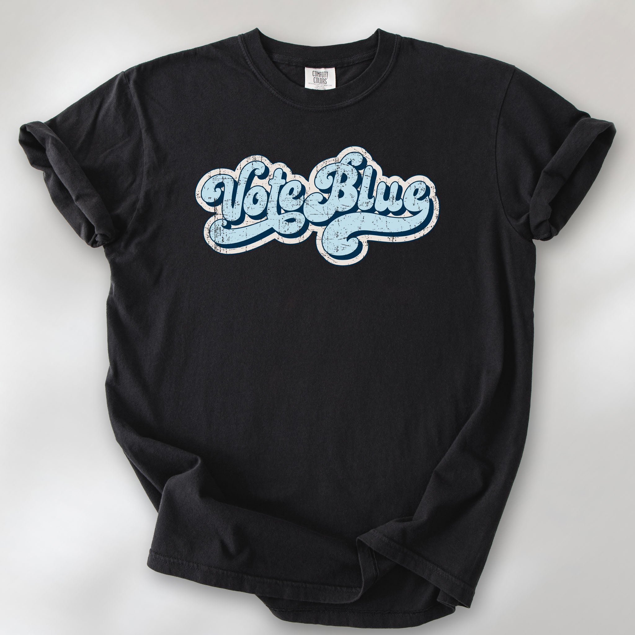 Black t-shirt featuring distressed retro script text reading "Vote Blue" in light blue vintage lettering.