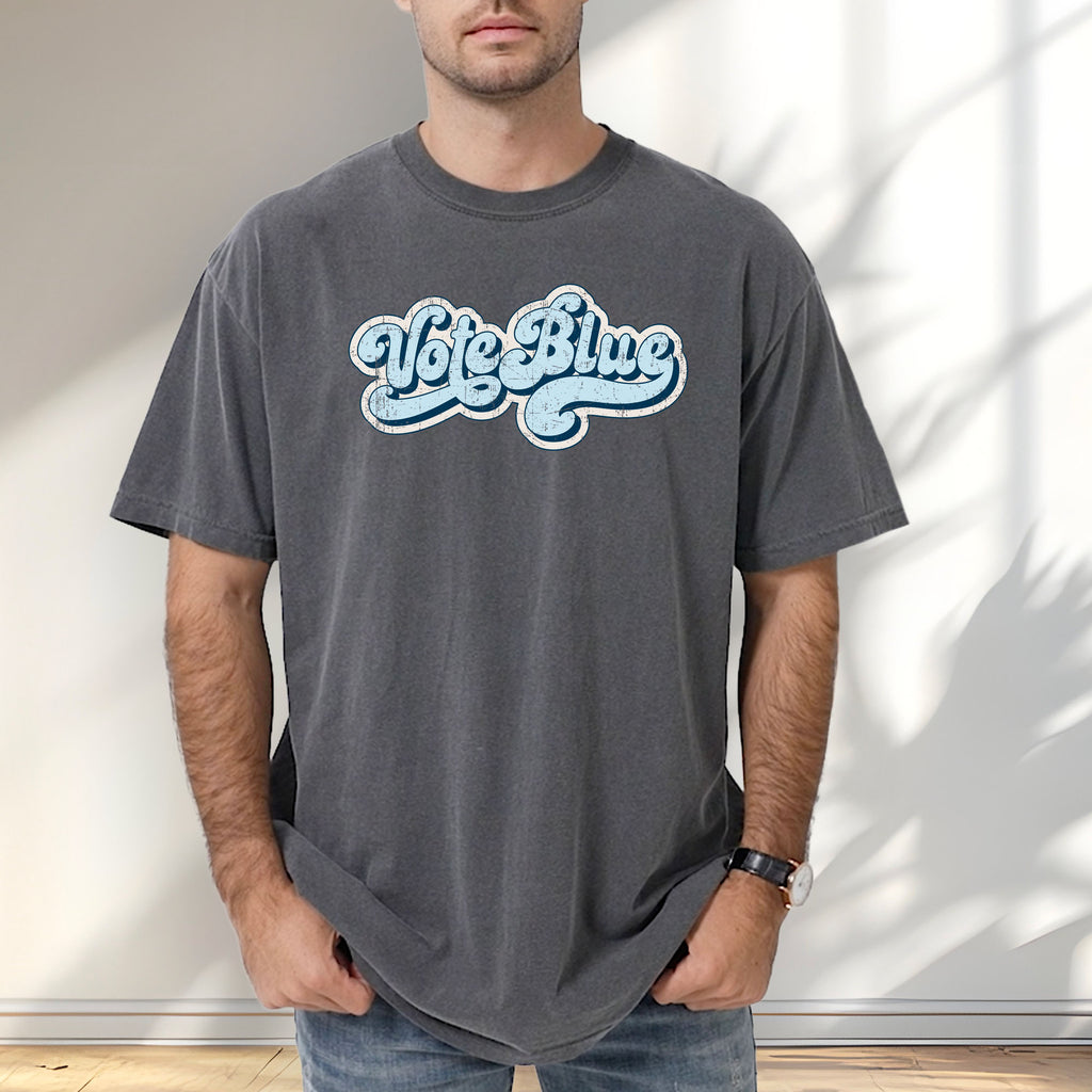 Male model wearing pepper t-shirt featuring distressed retro script text reading "Vote Blue" in light blue vintage lettering.