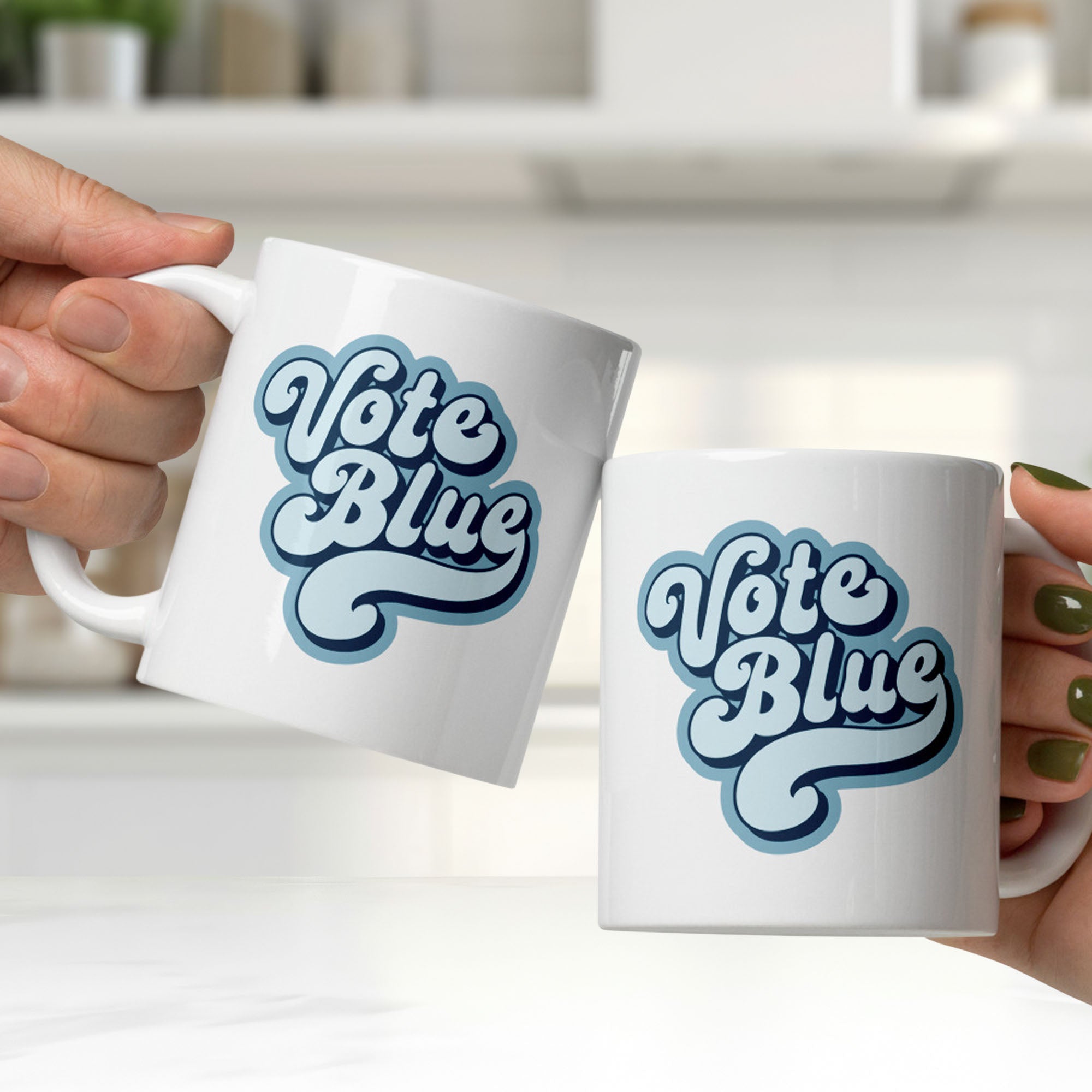 Two white ceramic coffee mug featuring a retro blue “Vote Blue” script design, being clinked together by two people in a white kitchen.