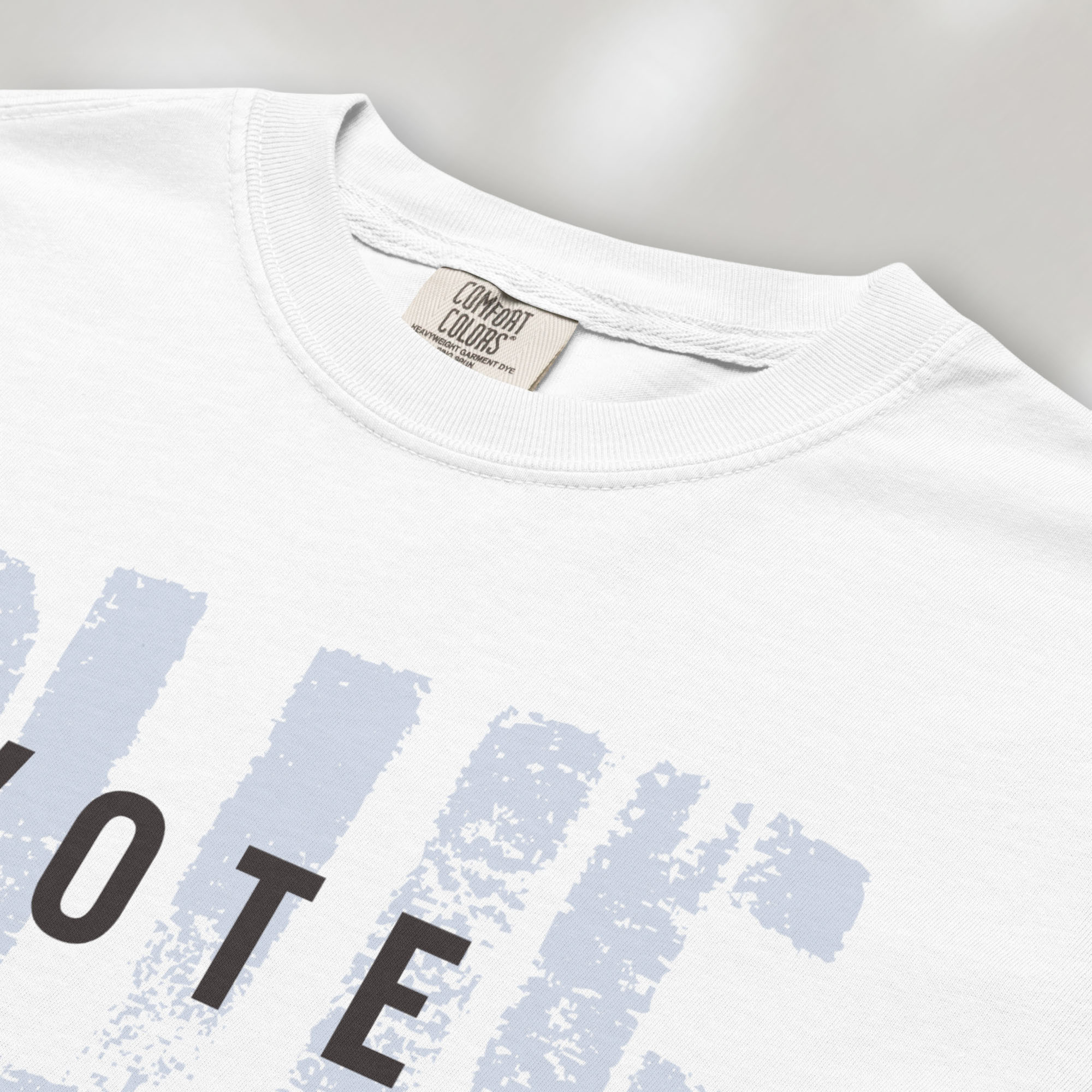 Closeup detail of white t-shirt with the word "vote" atop the word "blue" in a grunge background texture.