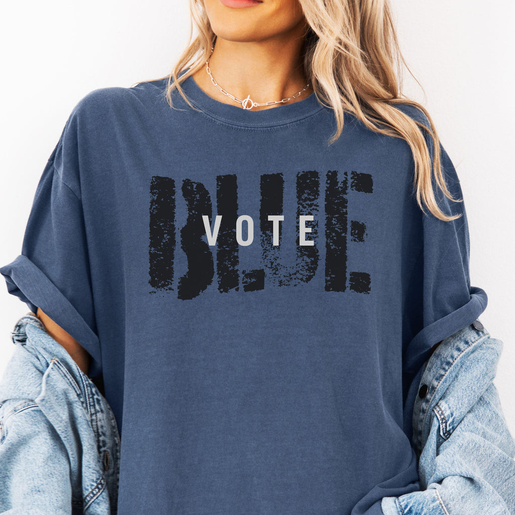 Female model wearing denim t-shirt with the word "vote" atop the word "blue" in a grunge background texture.