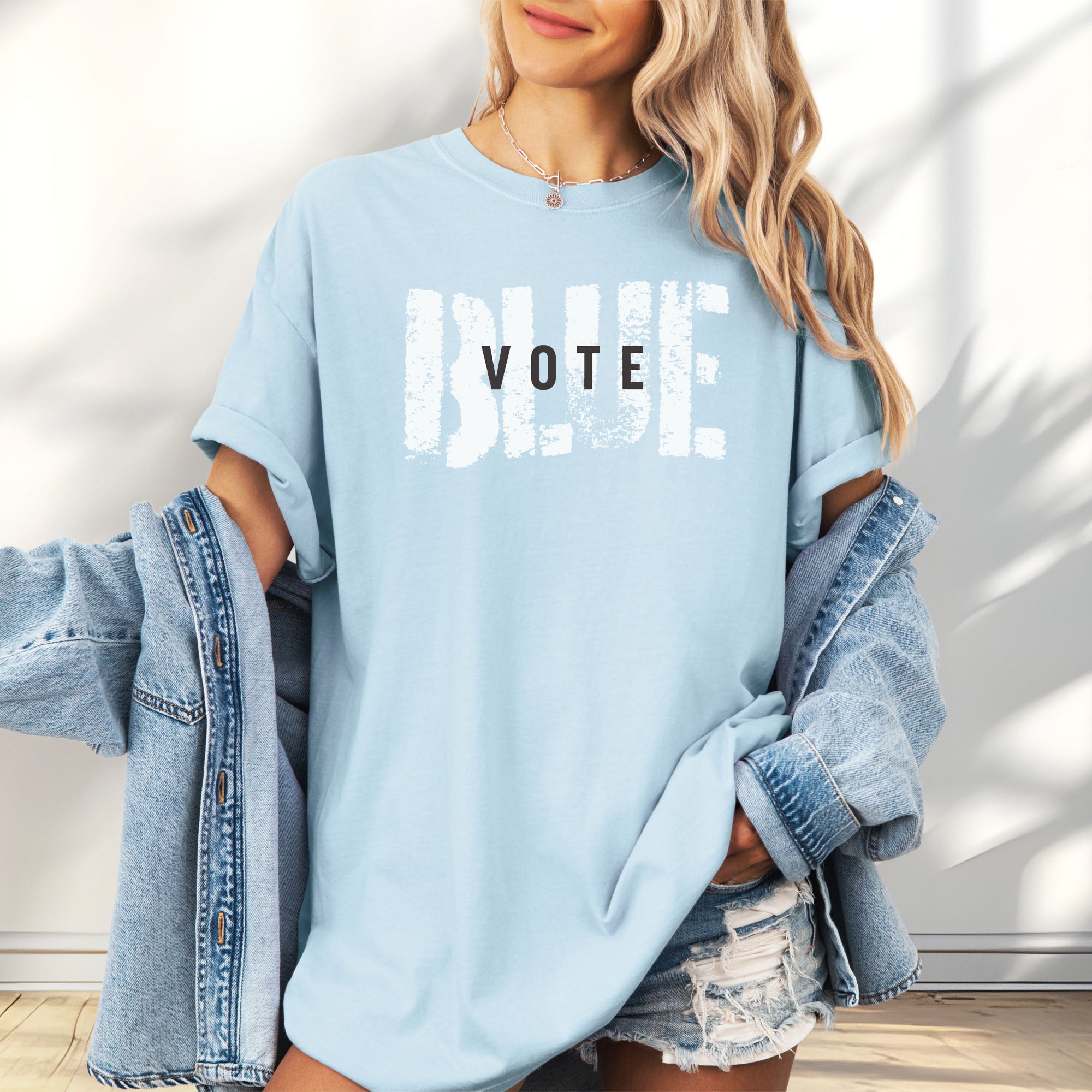 Female model wearing oversized chambray t-shirt with the word "vote" atop the word "blue" in a grunge background texture.