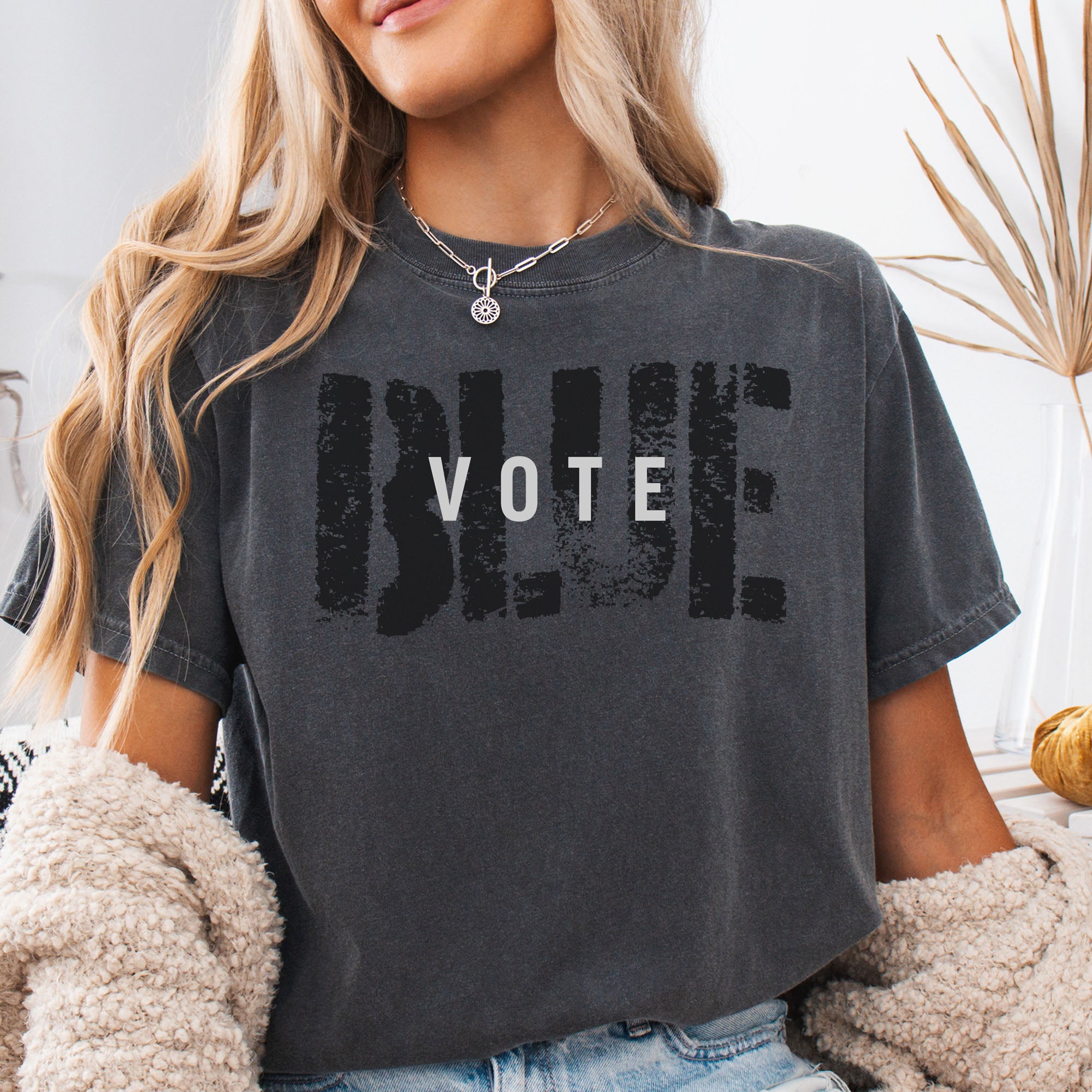 Female model wearing pepper t-shirt with the word "vote" atop the word "blue" in a grunge background texture.