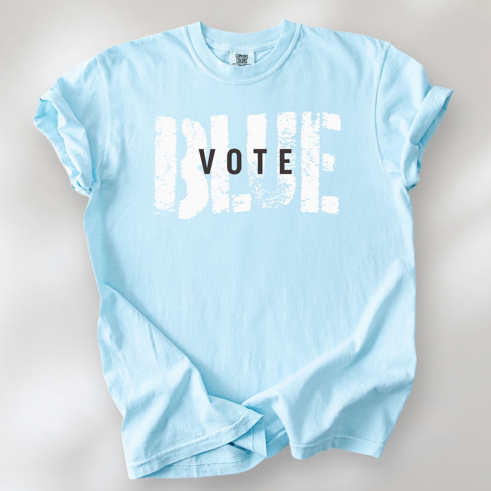 Chambray t-shirt with the word "vote" atop the word "blue" in a grunge background texture.
